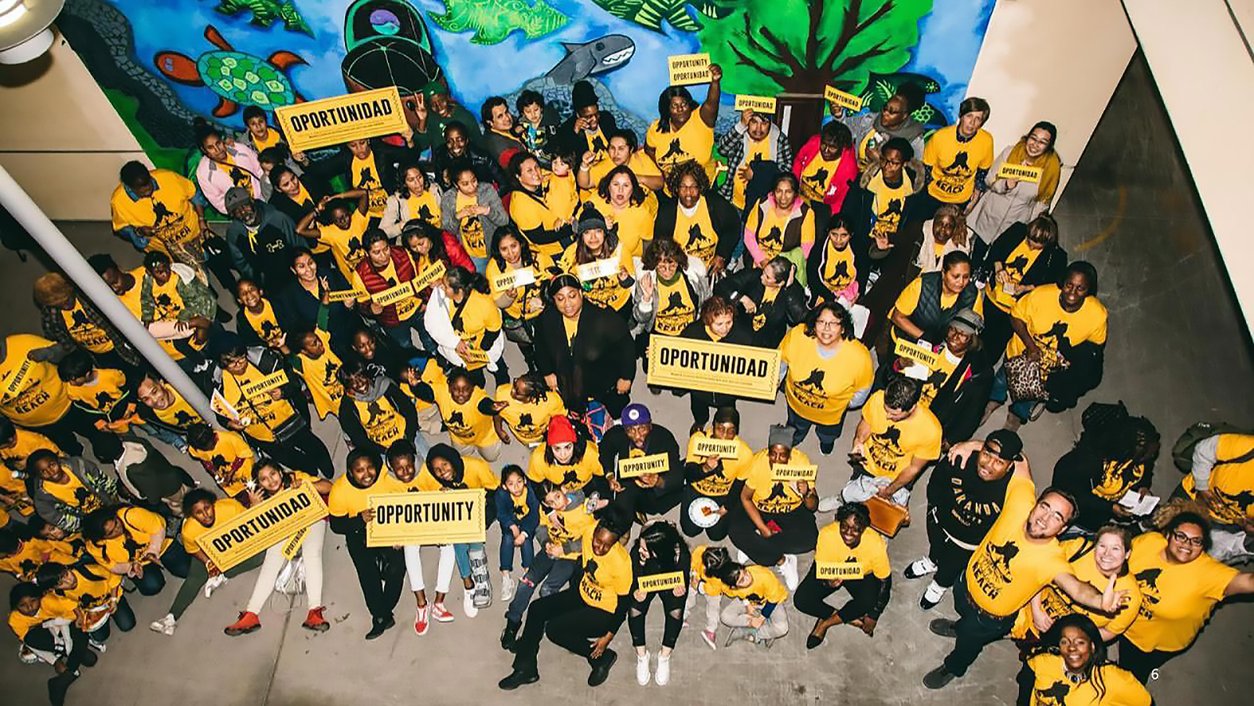 Smiling families with Oakland REACH shirts hold signs that say "opportunity"