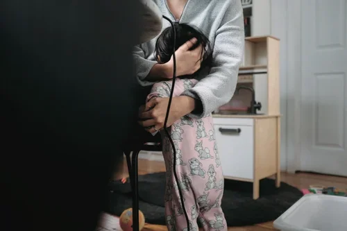 Parent working from home while embracing a toddler, reflecting the balance of parenting responsibilities and the support available through perinatal therapy and postpartum counseling.