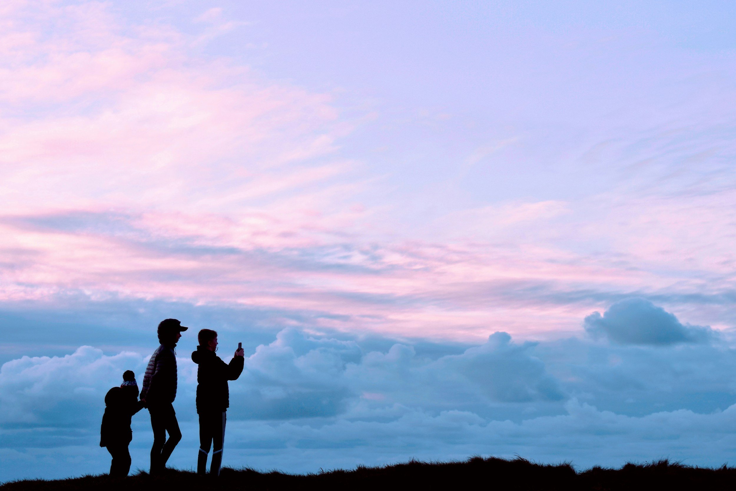 Parent and child connecting outdoors during a colorful sunset inspired by the transgender pride flag, representing gender identity counseling, transgender therapy and affirming support.