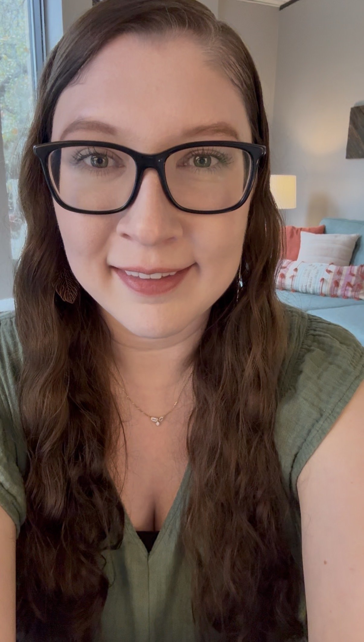 Caitlin Senger, LPC, wearing glasses with brown wavy hair, standing in front of a therapy couch. EMDR therapist offering EMDR intensive therapy in Texas.
