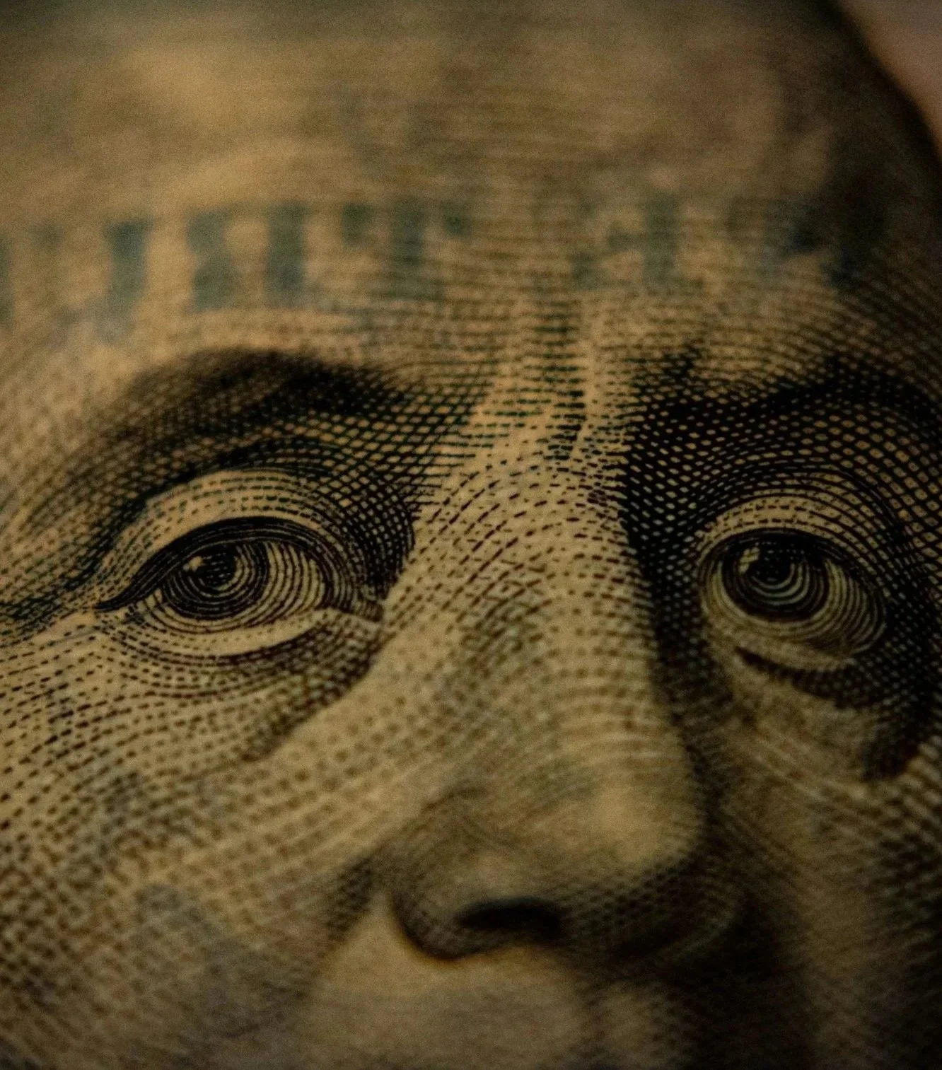 Close-up of a dollar bill showing detailed portrait of Benjamin Franklin's face.