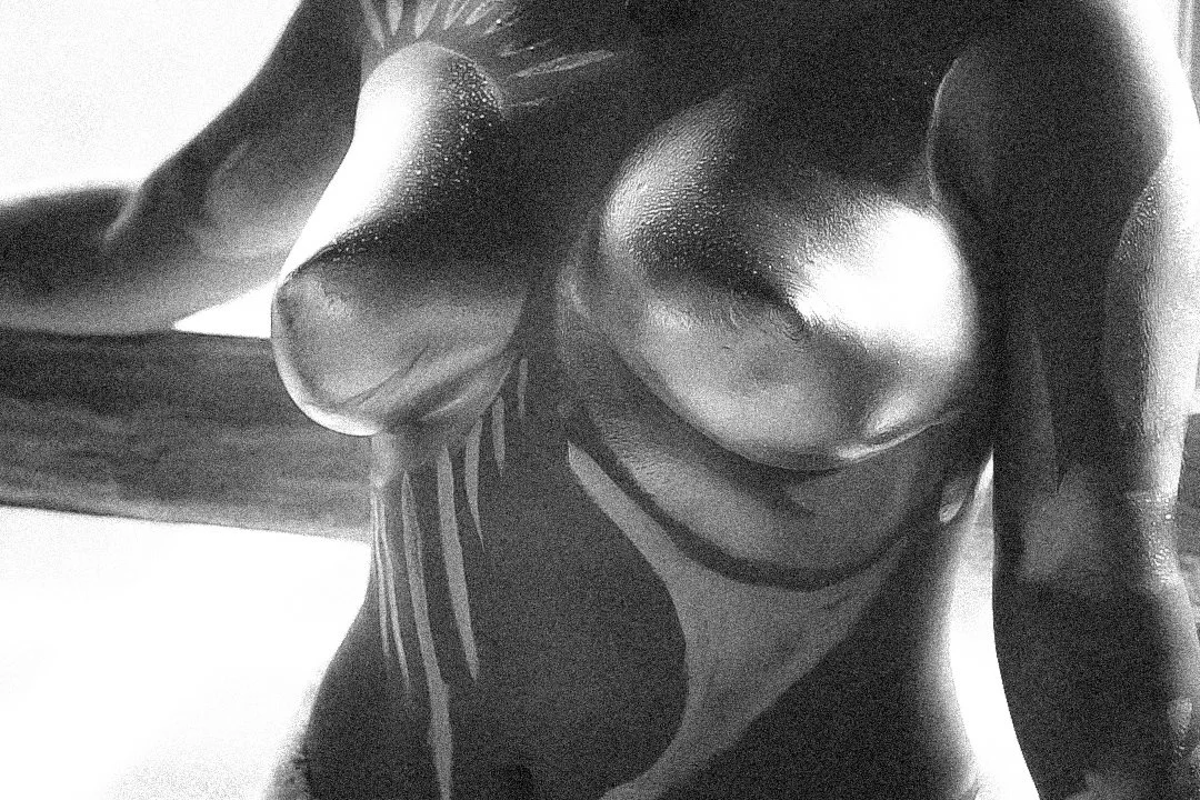 Close-up of a black and white figurine with a muscular upper body, showing the chest, shoulders, and part of the arms.
