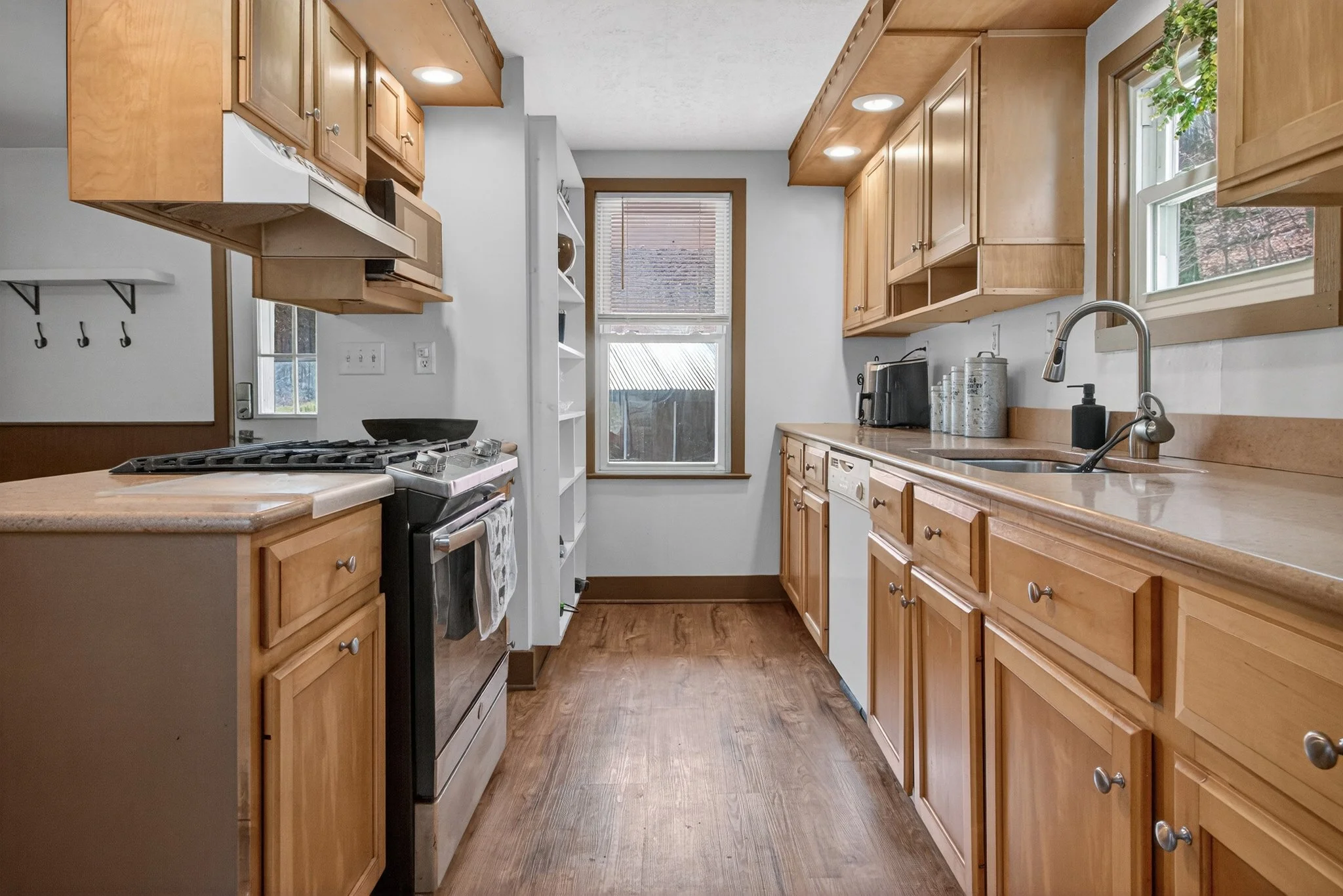 Kitchen with wooden cabinets, a window, countertop, stove, and small appliances.