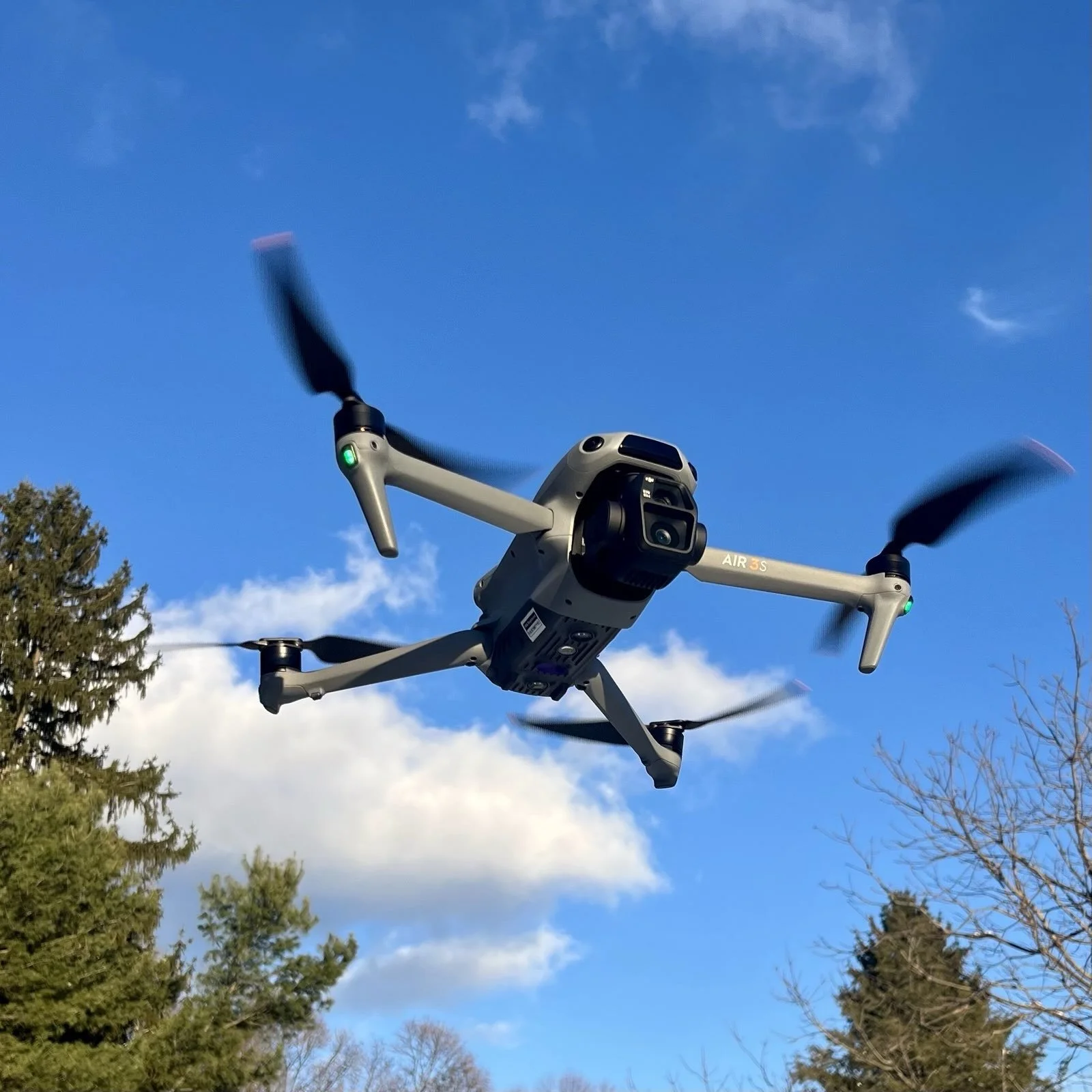 A drone flying near a power line tower against a blue sky.