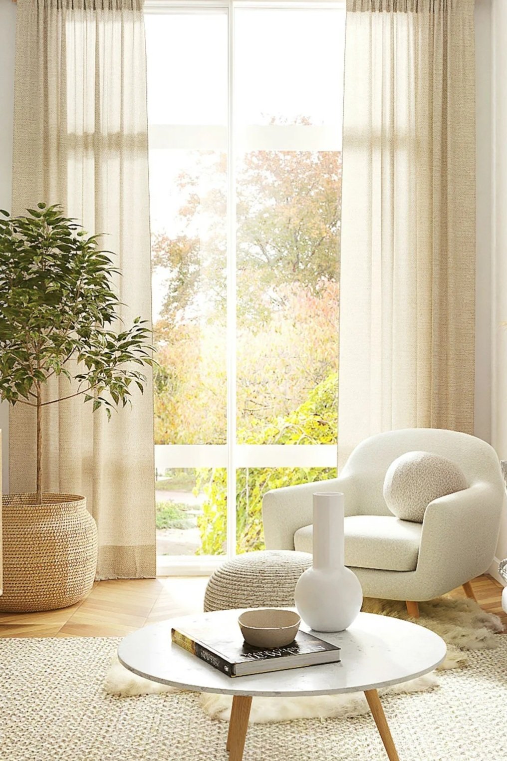 Bright living room with large window and curtains, white armchair with pillow, potted plant, round coffee table with decorative items, and a cozy rug.