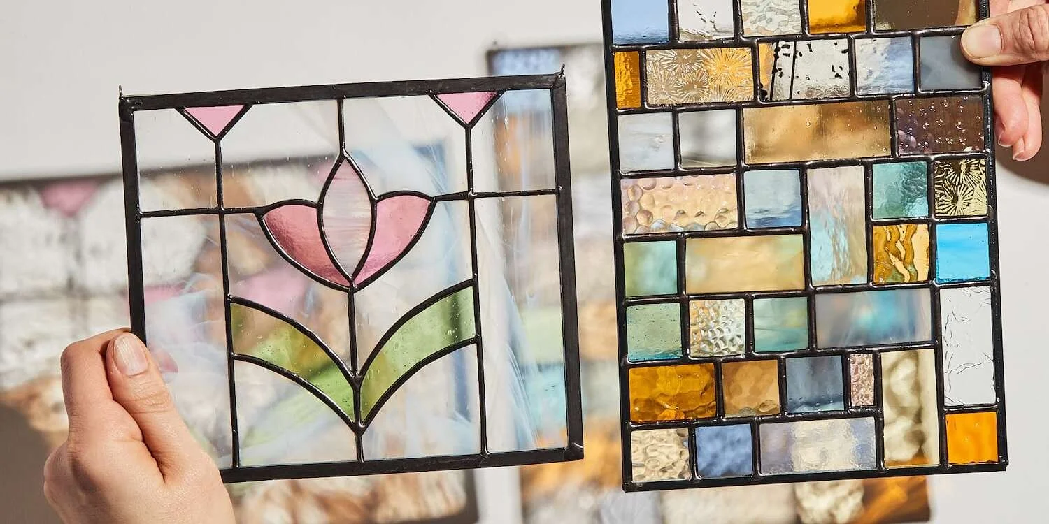 Two stained glass window panels with floral and mosaic patterns held by hands.