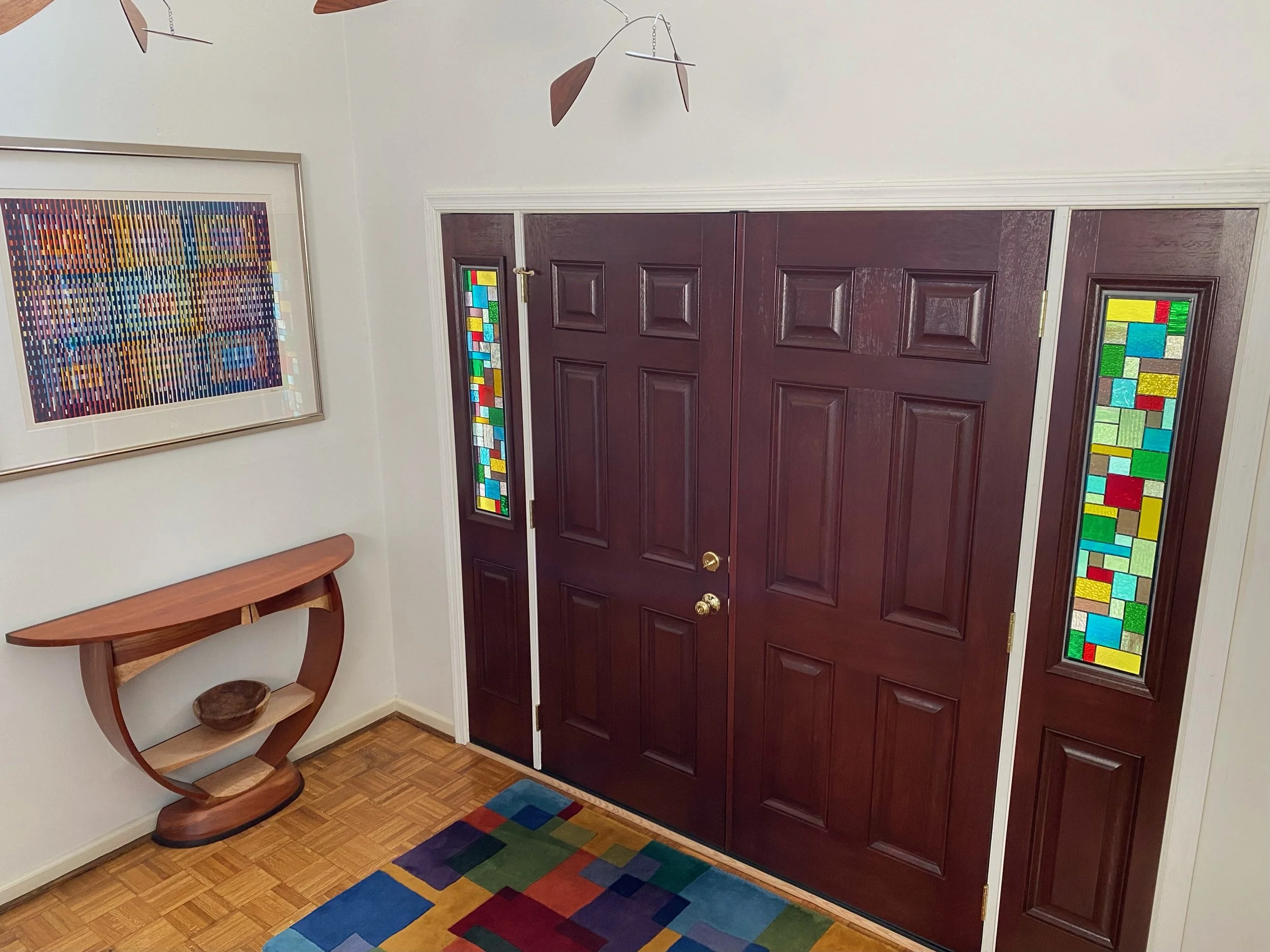 Entrance door with stained glass side windows and colorful carpet.