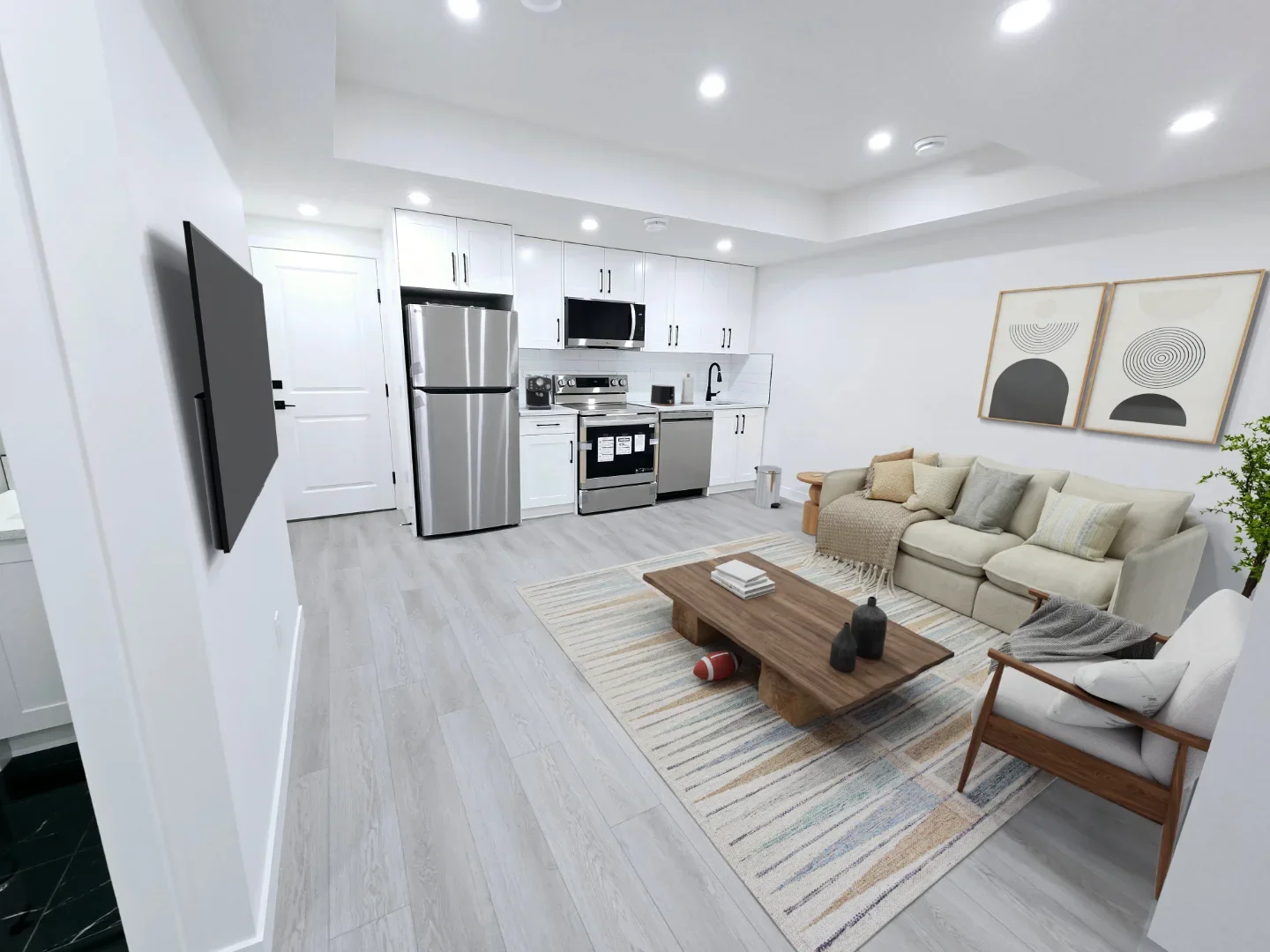 A fully staged living room with a beige sofa and wooden coffee table, showing how the space flows into the modern kitchen.