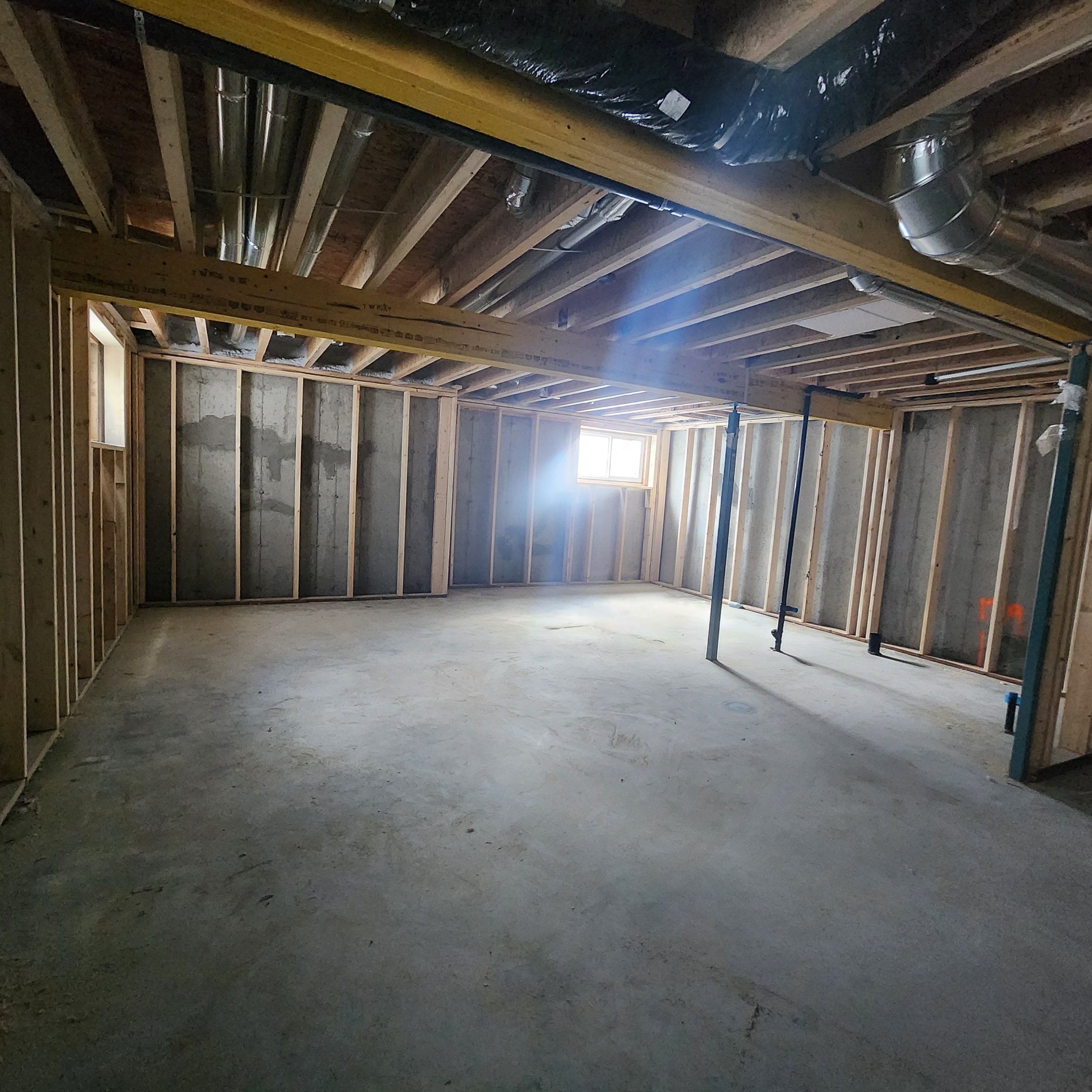 dark undeveloped basement with concrete flooring and open joist spaces
