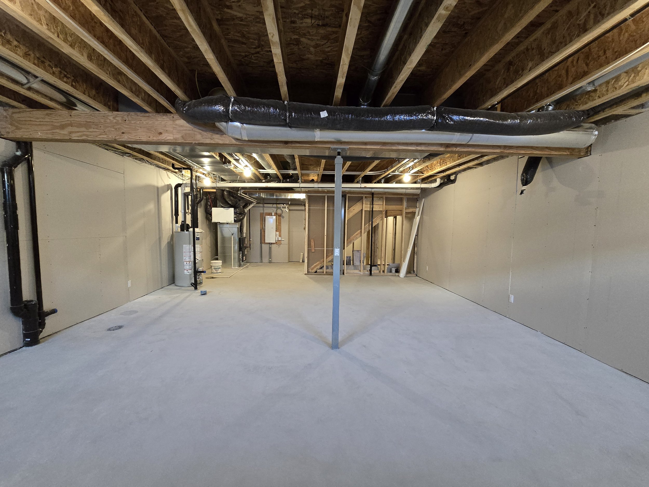 Wide open unfinished basement with exposed joists and mechanicals, ideal for Calgary basement development planning, layout design, and future legal suite conversion.