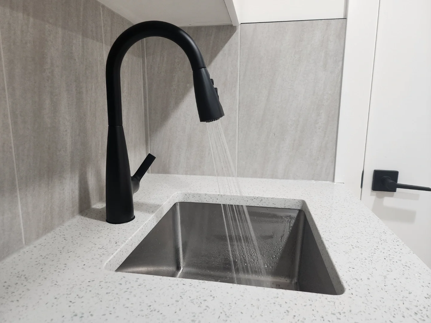 matte-black-kitchen-faucet-running-water.webp