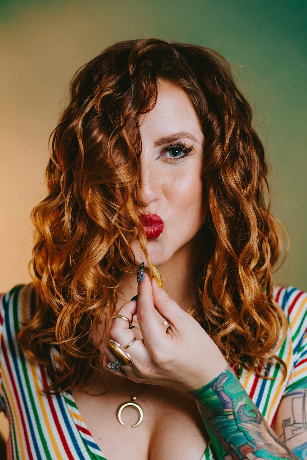 woman with red curly hair making kissy face with red lipstick and gorgeous long eyelashes