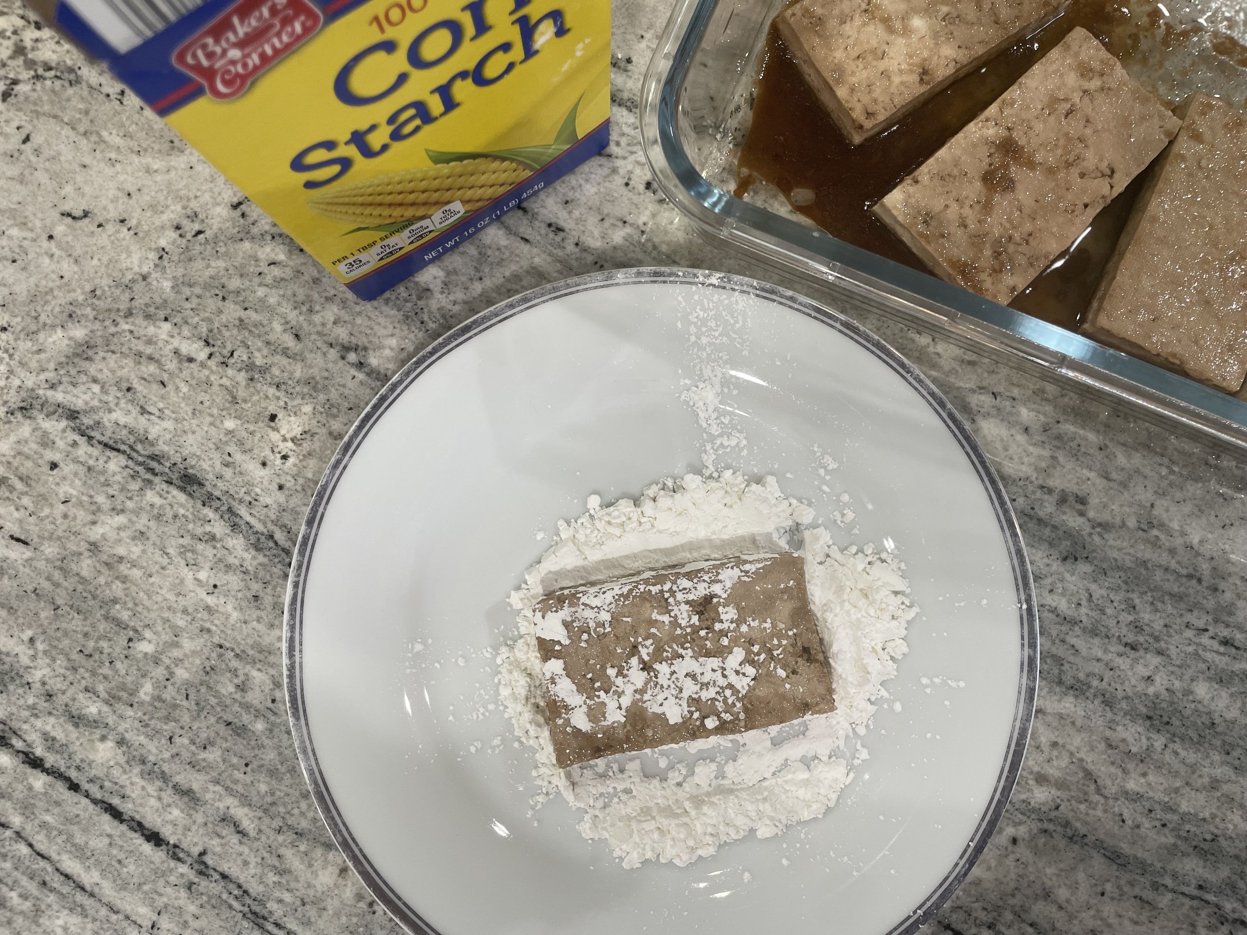 Coating tofu pieces in cornstarch to create a crispy exterior when baked