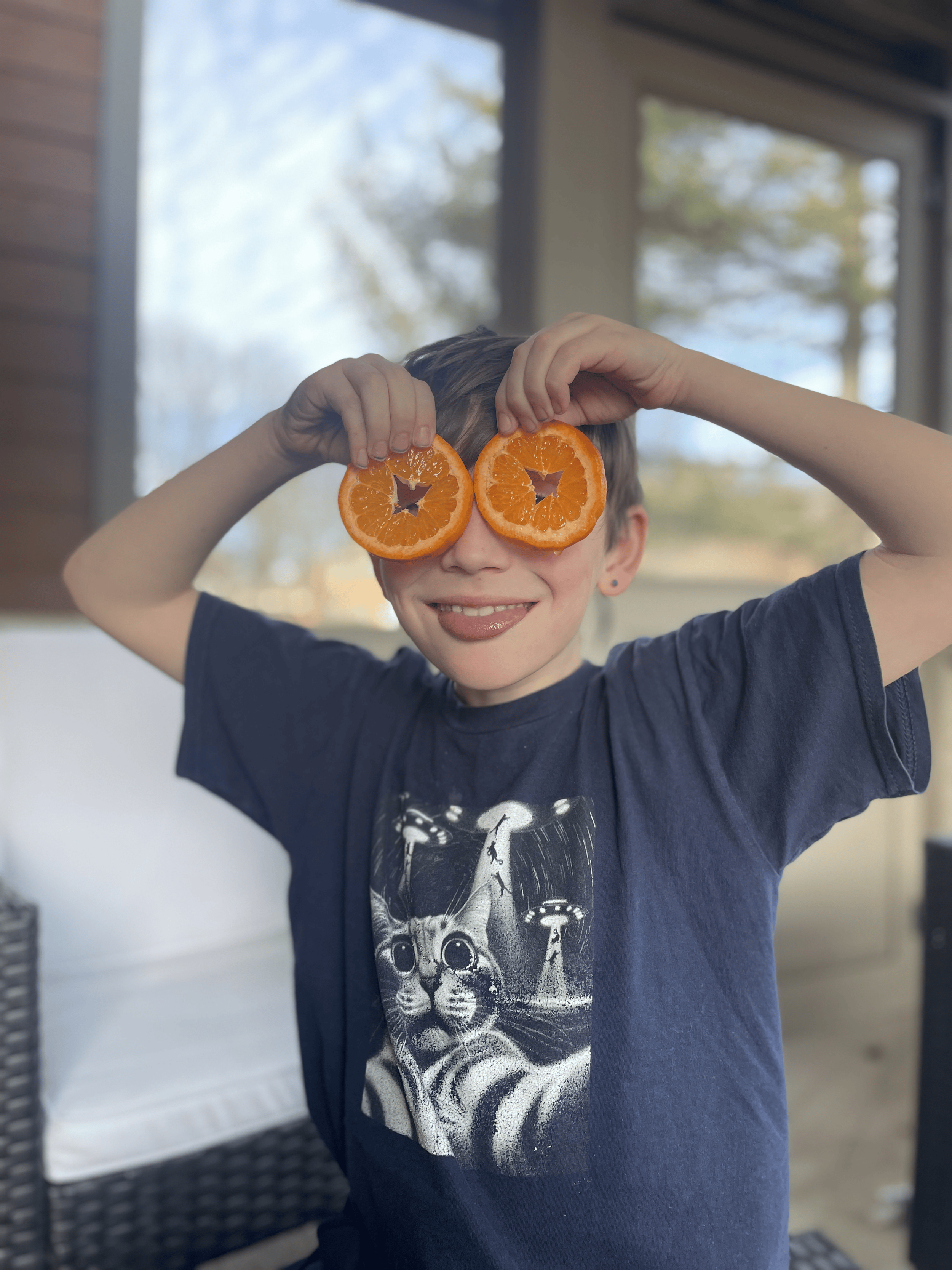 boy holding up slices of oranges over his eyes