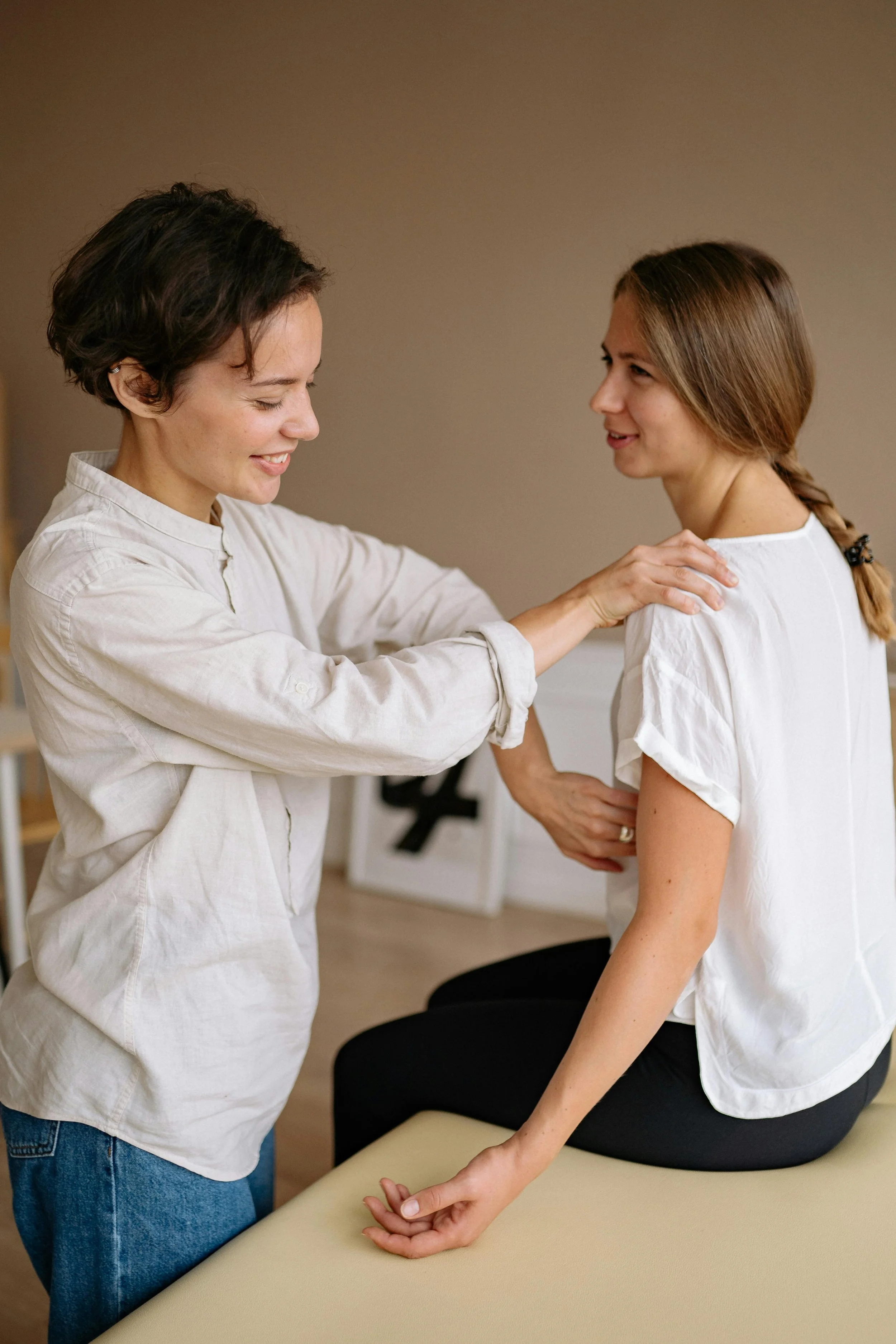 A healthcare professional examining a woman's shoulder in a clinical setting.