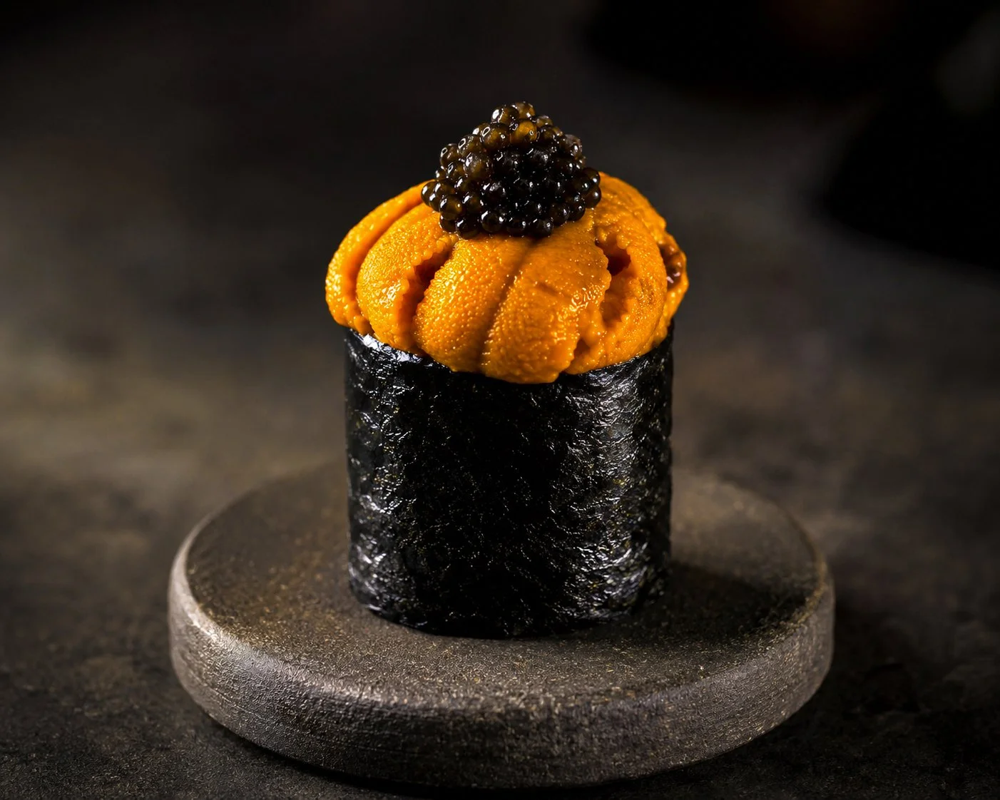 Sushi roll with sea urchin, topped with black caviar, wrapped in nori seaweed.