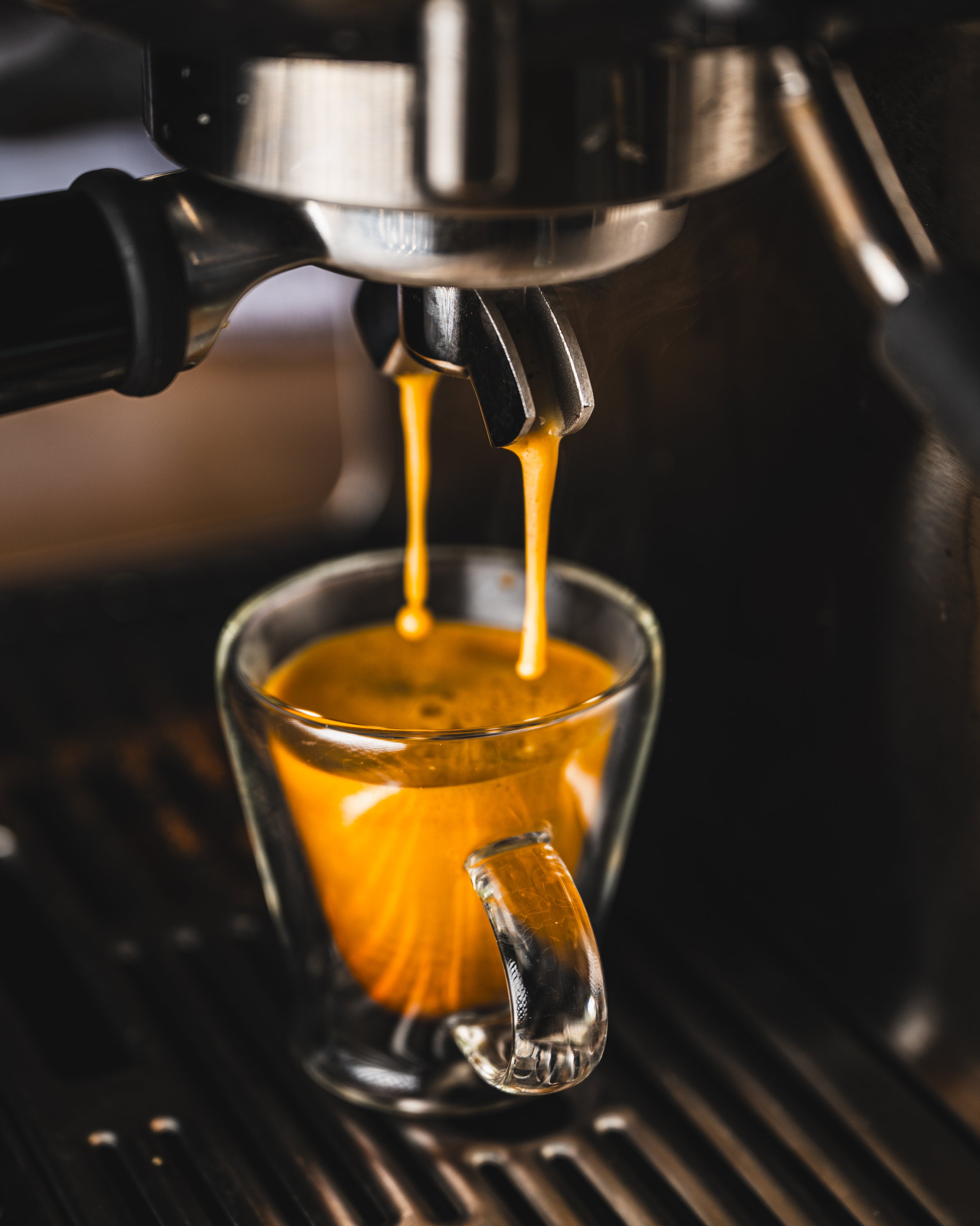 A close-up of a coffee machine brewing espresso into a glass mug.