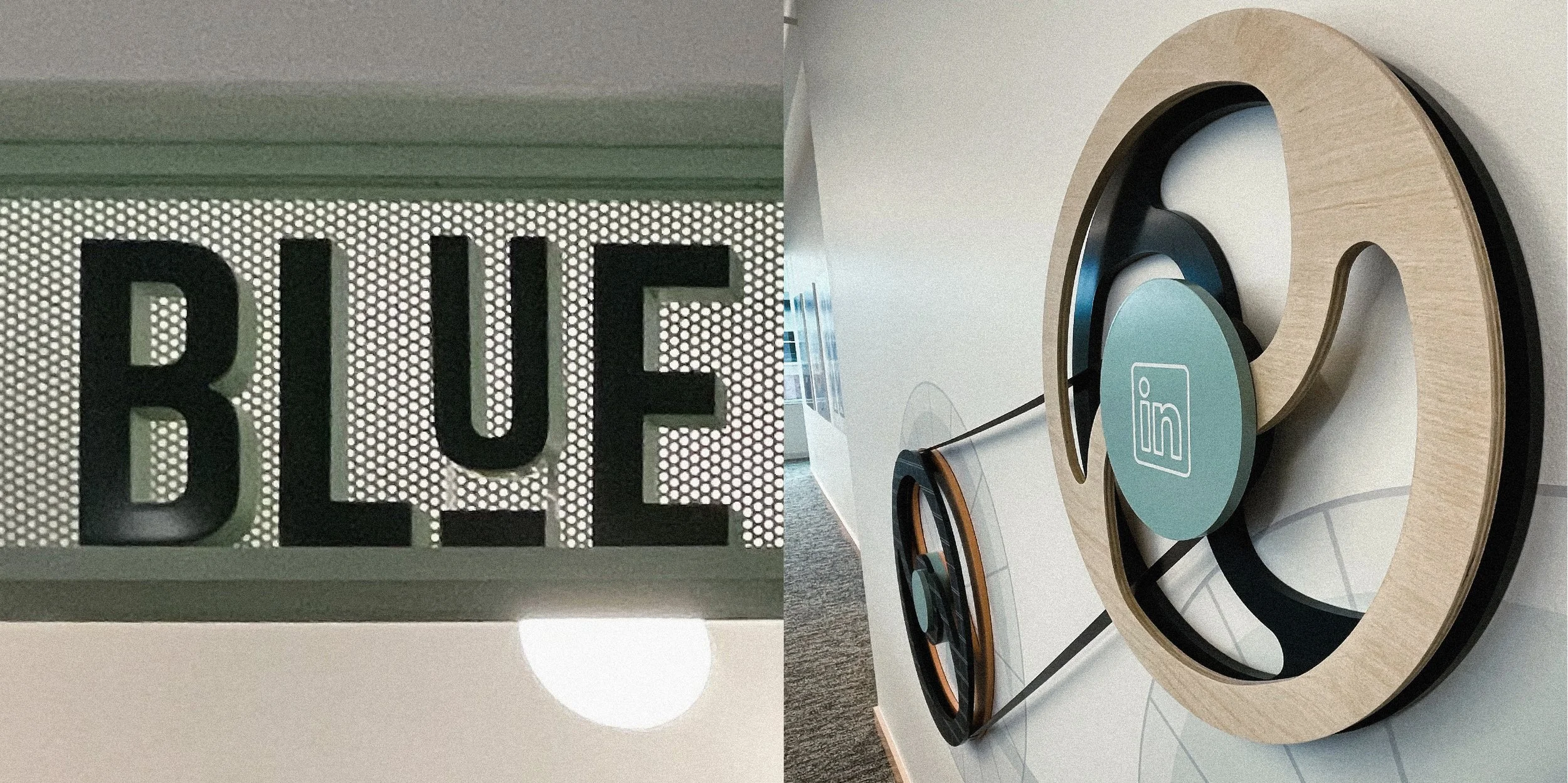 A close-up of a lighted sign with the word 'BLUE' in black capital letters, mounted on a patterned background. Next to it, a modern table exhibits a wooden circular sculpture, a teal circular object with an 'im' logo, and a black and orange object co