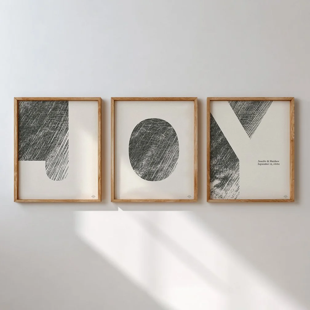 Three framed abstract art prints with black shapes and textures on white backgrounds hanging on a white wall.