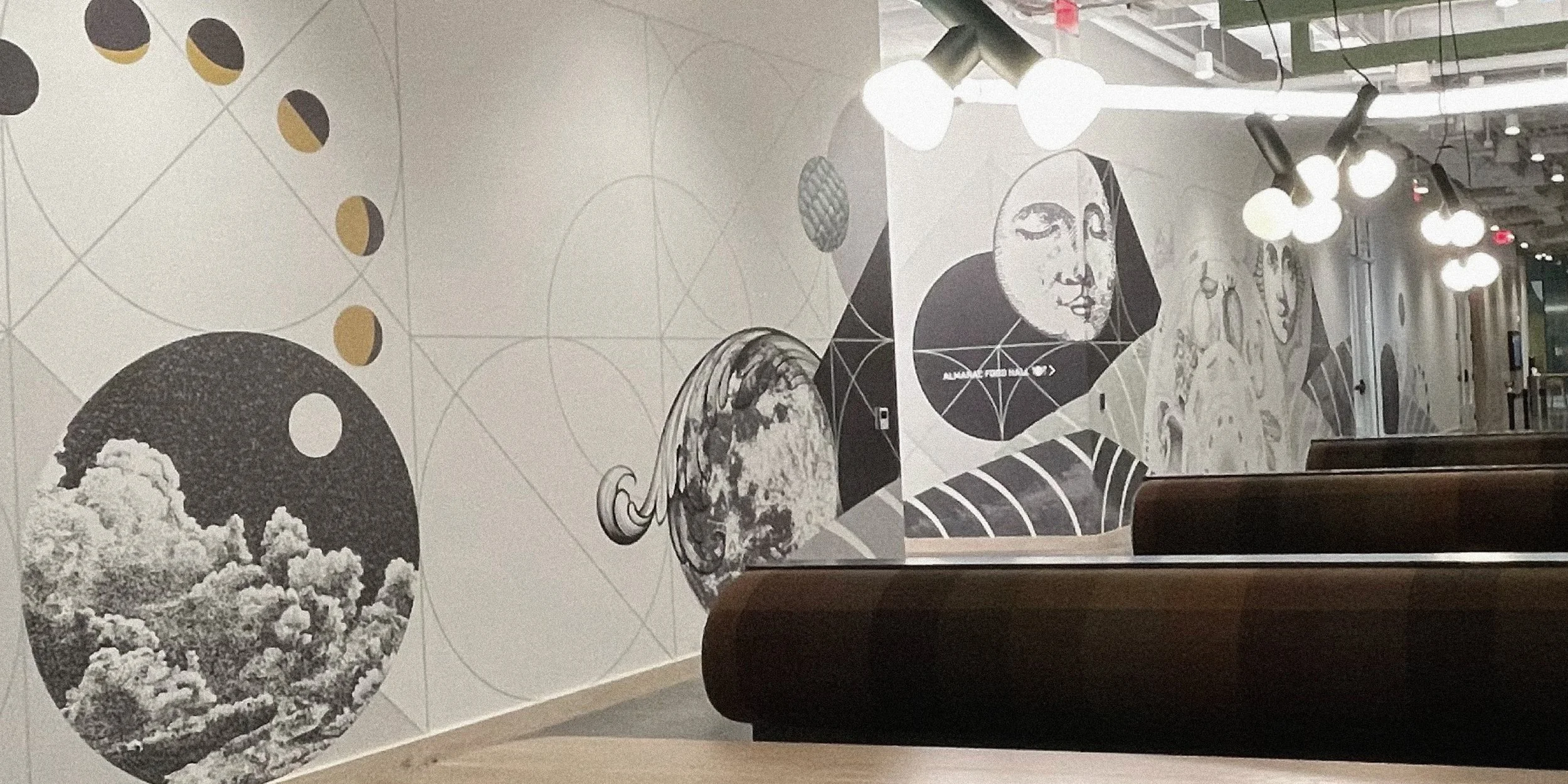 Mural on a wall featuring geometric shapes, moon phases, and artistic portraits in a modern interior space with overhead lighting.