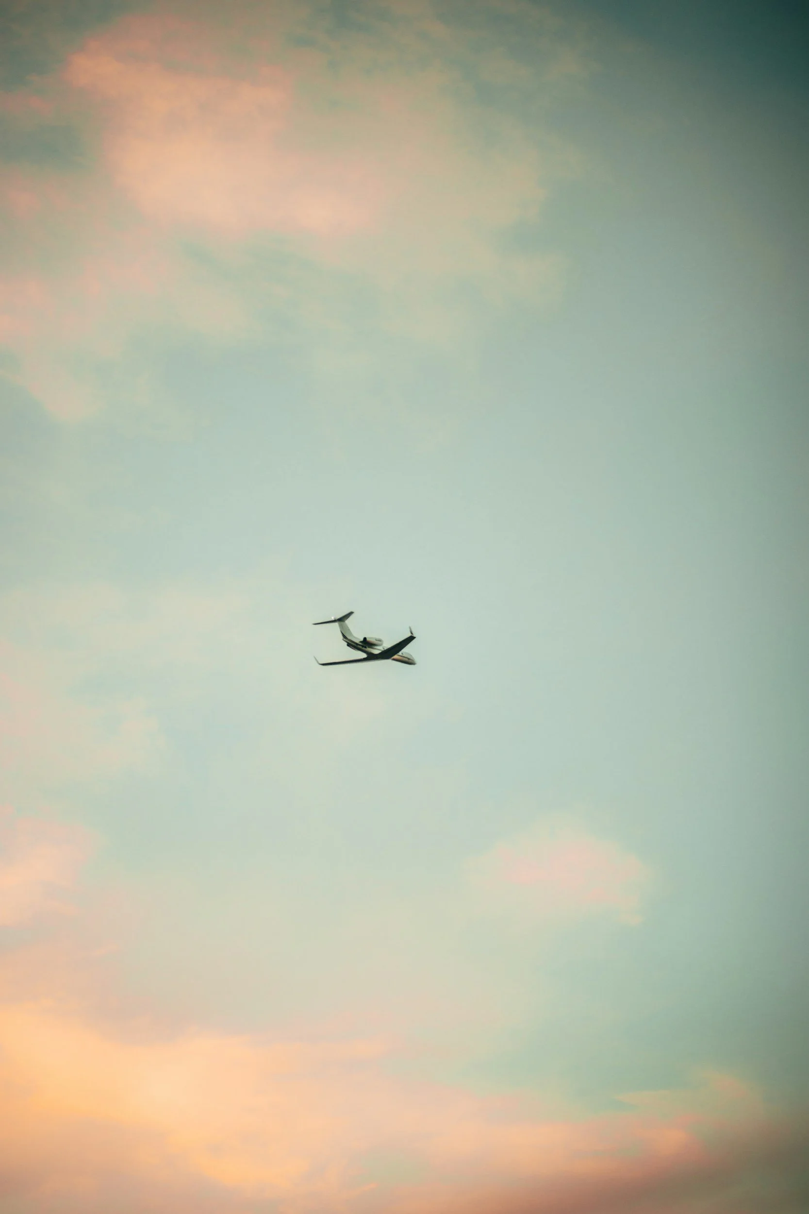 Two airplanes flying in the sky during sunset with pastel-colored clouds.