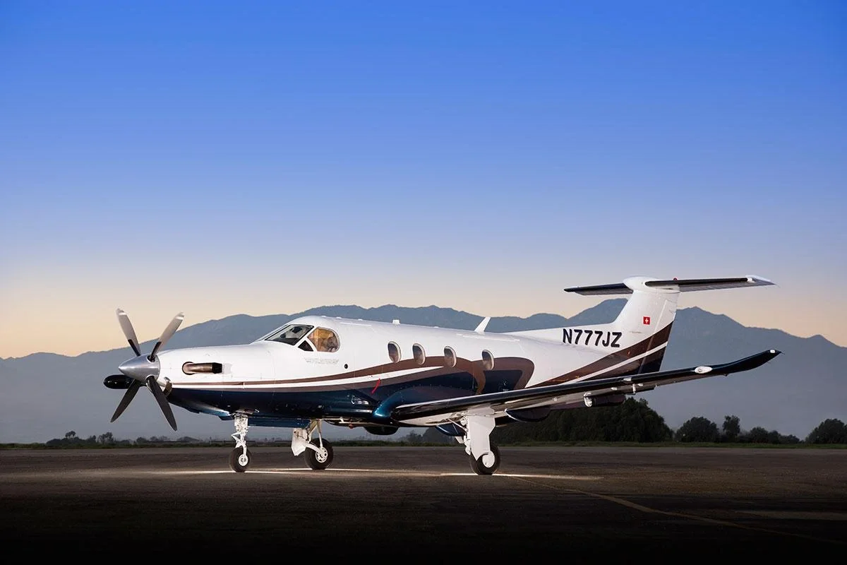 Private jet parked on runway during sunset with mountains in background.
