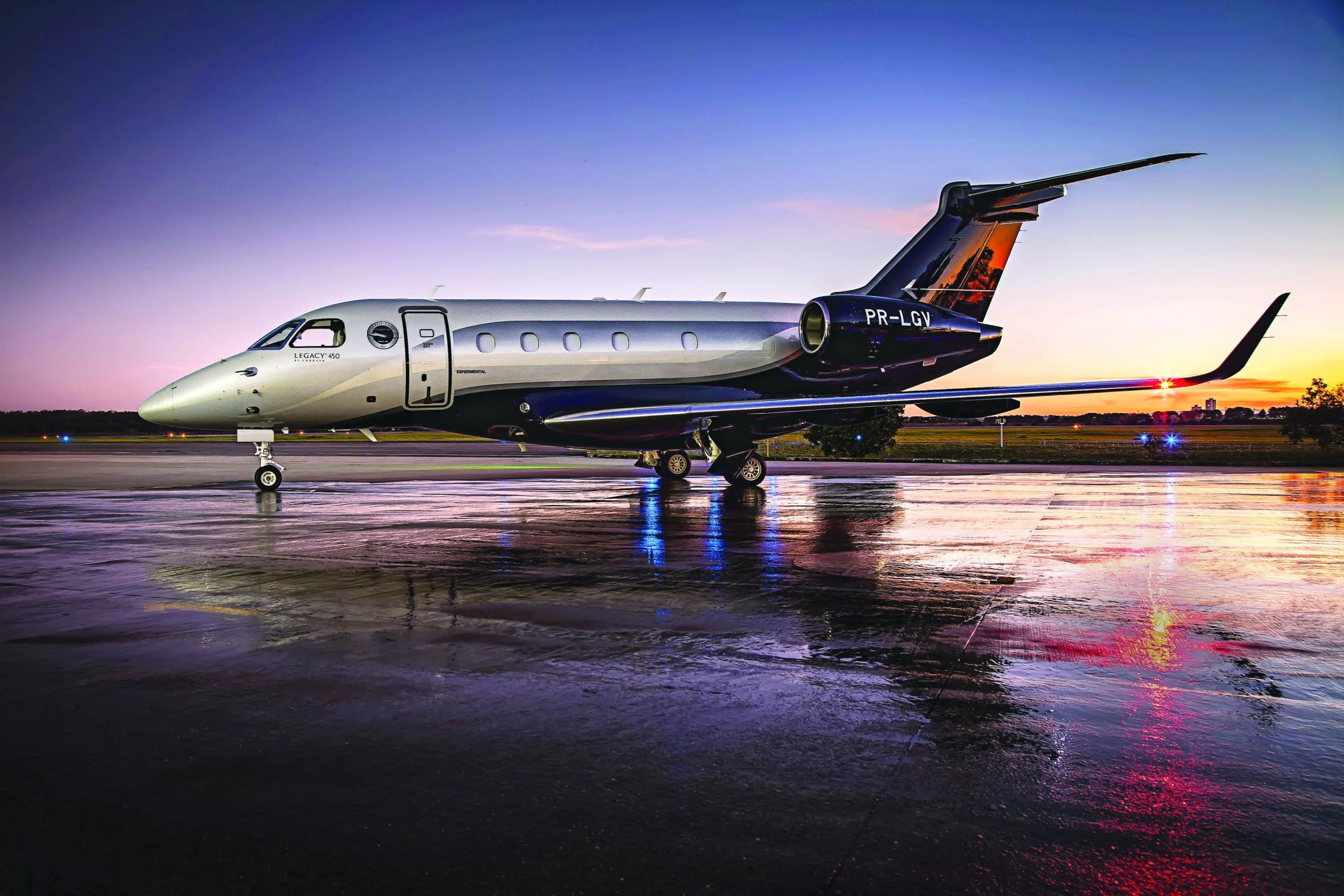 Luxury private jet parked on wet tarmac during sunset