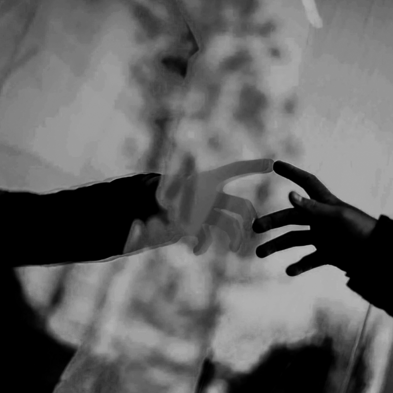 A person blowing smoke while another person touches the smoke with their hand, in a black and white image.