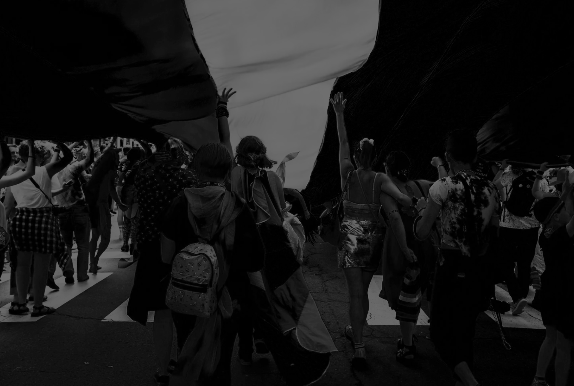 People participating in a protest or demonstration, holding up a large banner or fabric overhead.