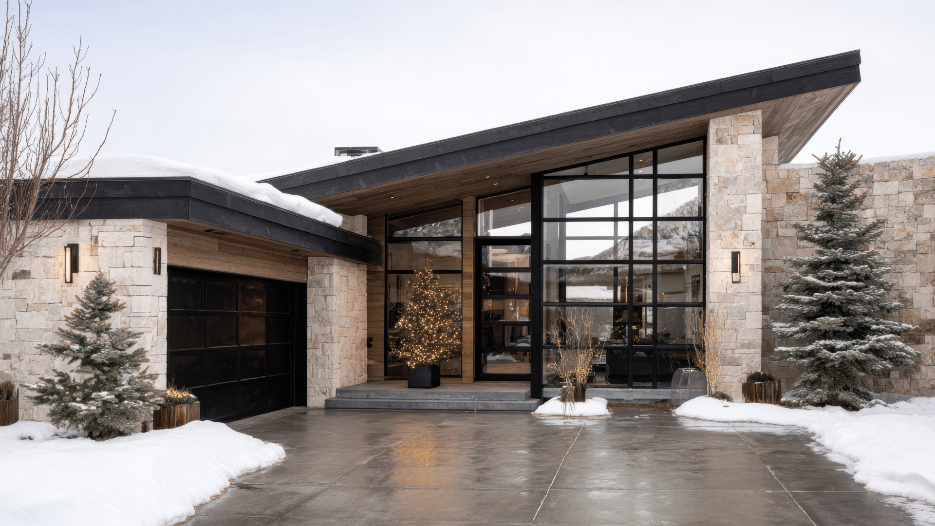 Modern house exterior with large glass windows, stone walls, snow-covered ground, and decorated Christmas trees.