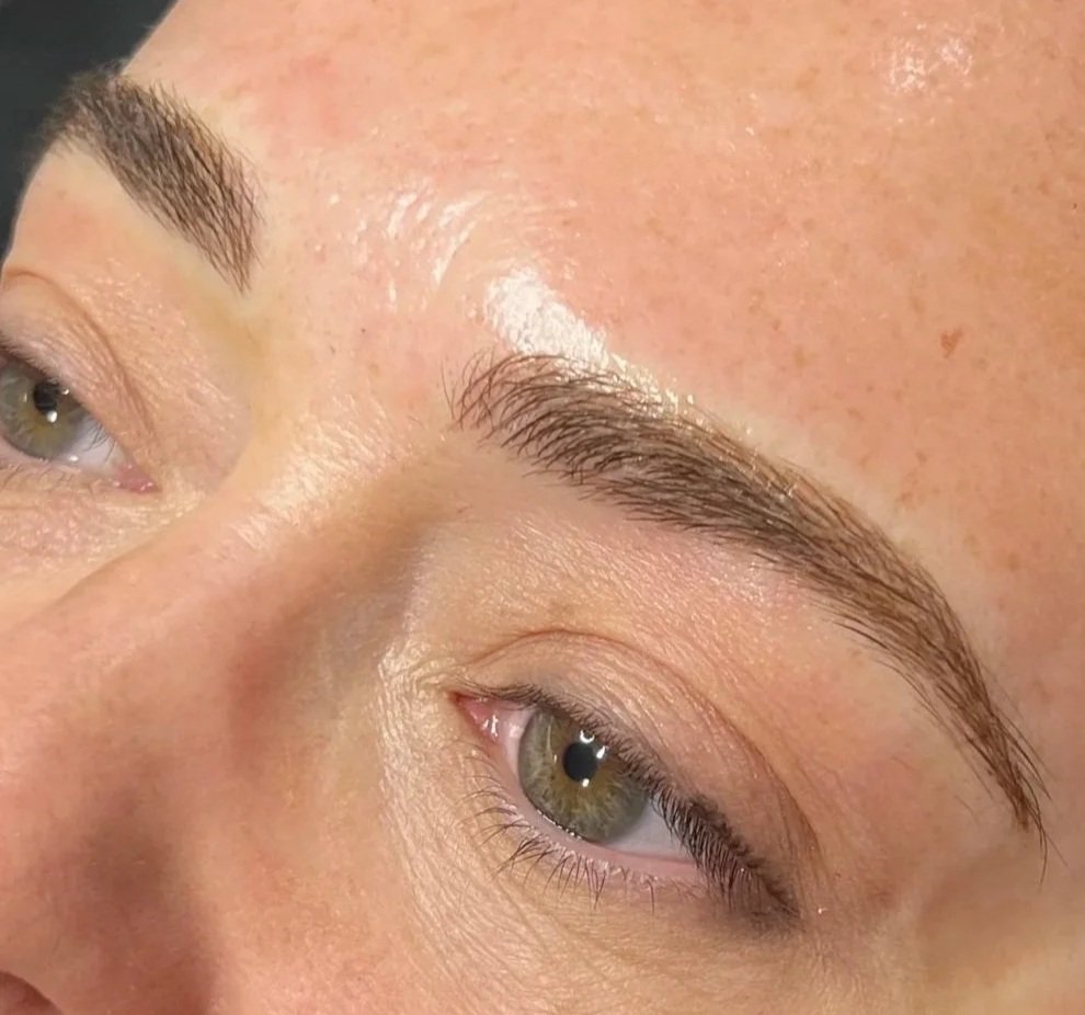 Close-up of a person's face showing fresh microbladed eyebrows.