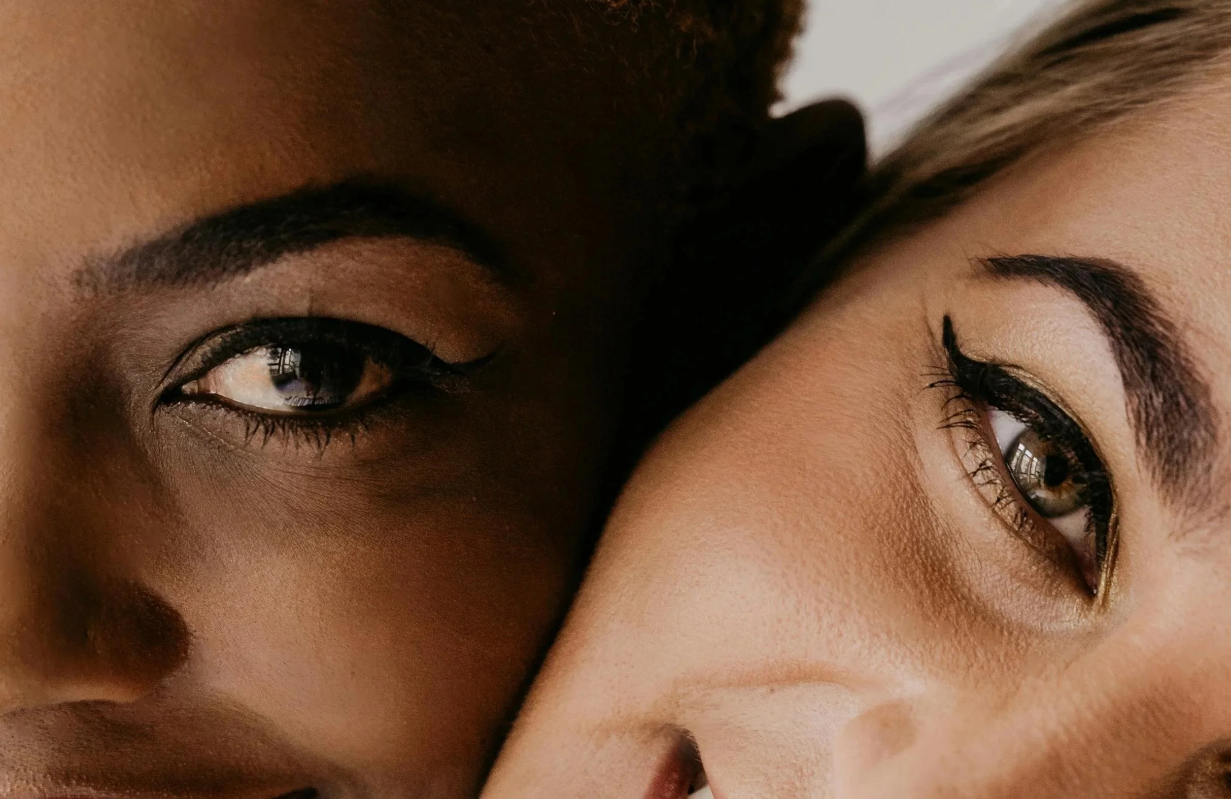 Close-up of two women's faces with their eyes and eyebrows visible, facing each other in close proximity.