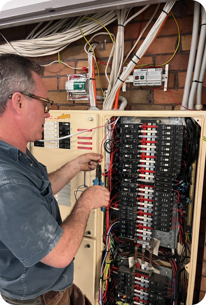 New Lambton Electrician - A technician working on an electrical circuit breaker panel with multiple wires and components.