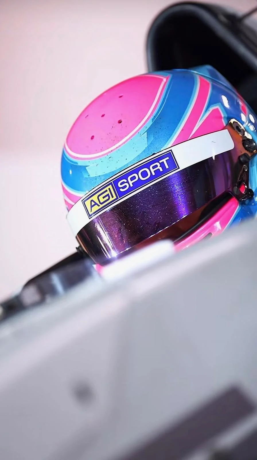Close-up of a colorful Arai motorcycle helmet, with pink, blue, and purple swirls, on a white surface.