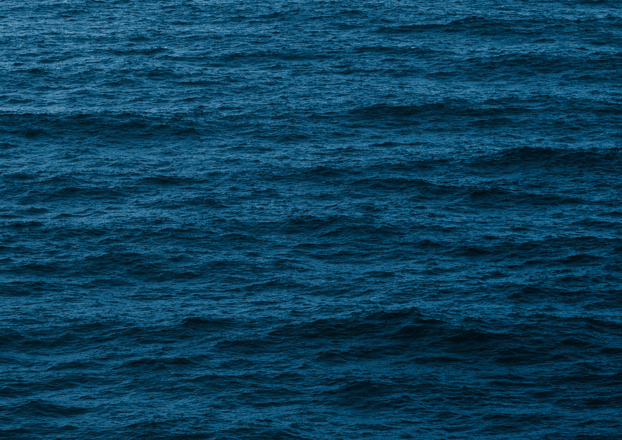 Mar aberto com ondas rolando na água de tom azul escuro.