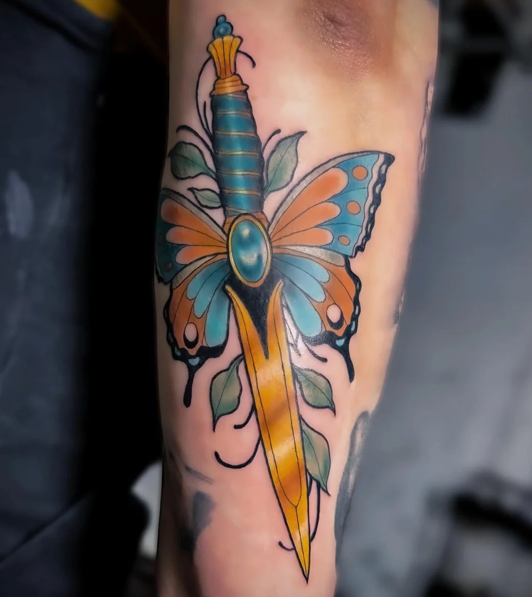 Colorful tattoo of a morphing butterfly with a sword-like body on a person's arm.