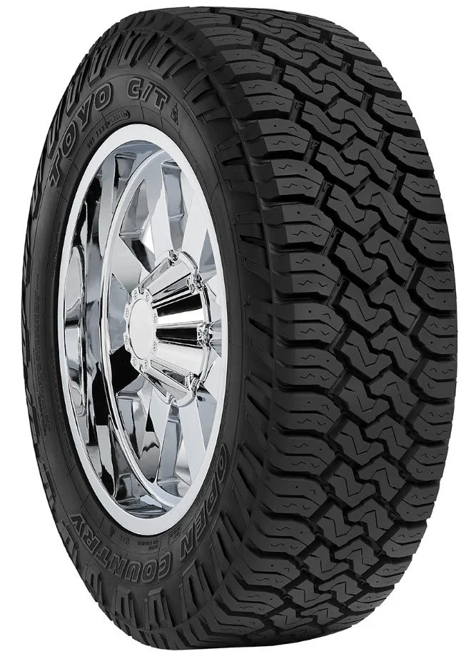 Close-up of a black all-terrain tire with deep tread pattern mounted on a shiny chrome wheel rim.