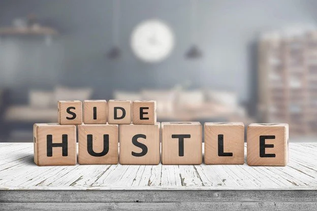Wooden blocks spelling 'SIDE HUSTLE' on a rustic white table.