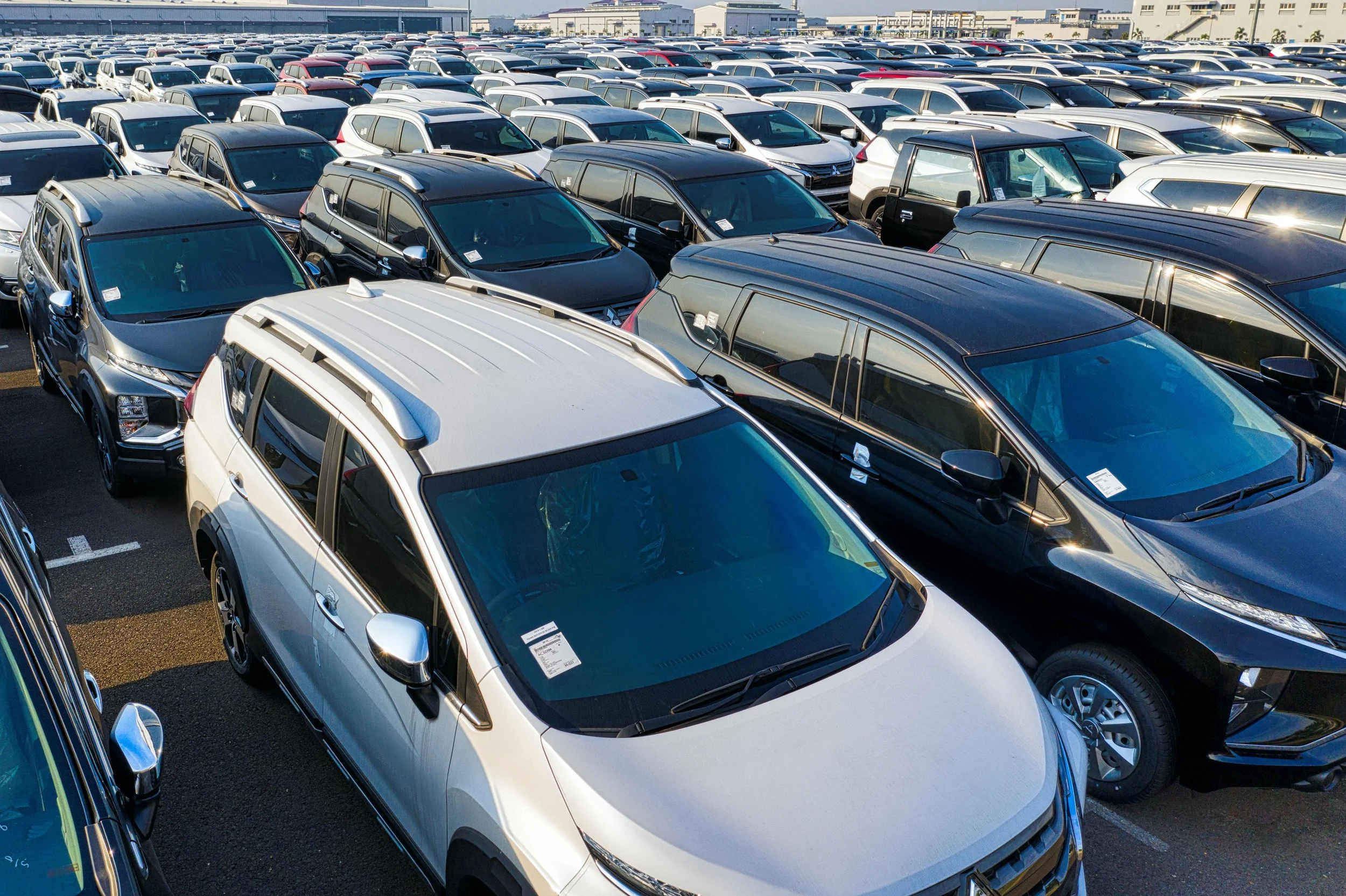 A large parking lot filled with numerous modern SUVs and cars parked in neat rows under clear weather.