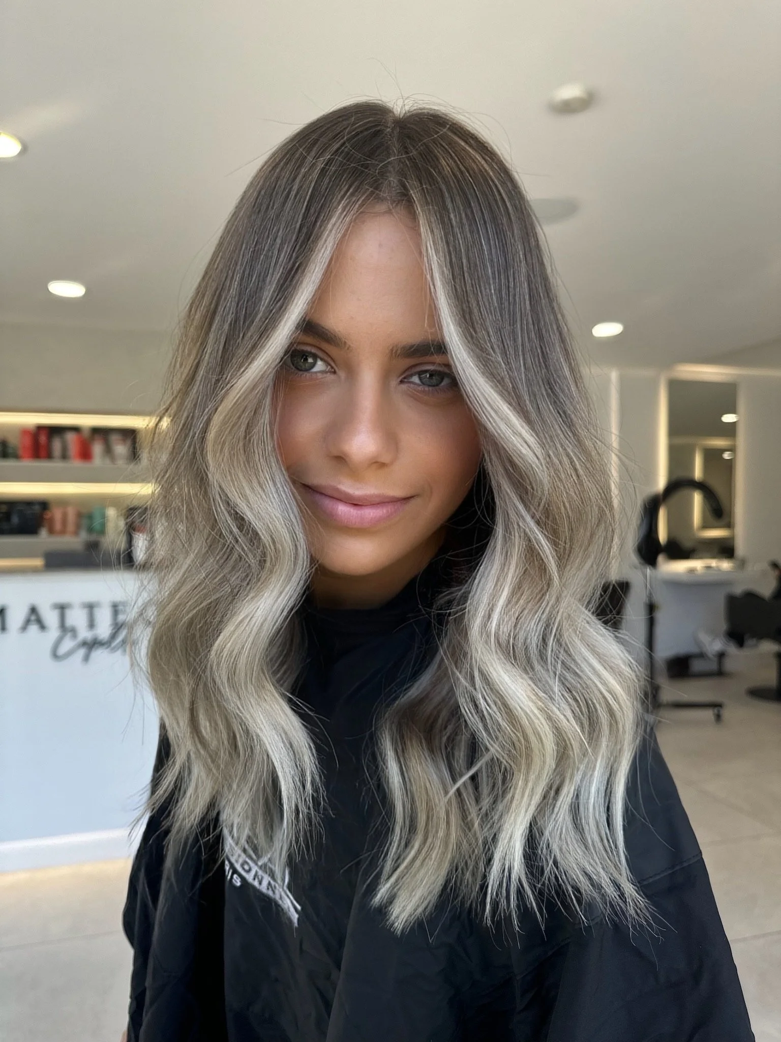Young woman with long, wavy blonde and brown hair at hair salon