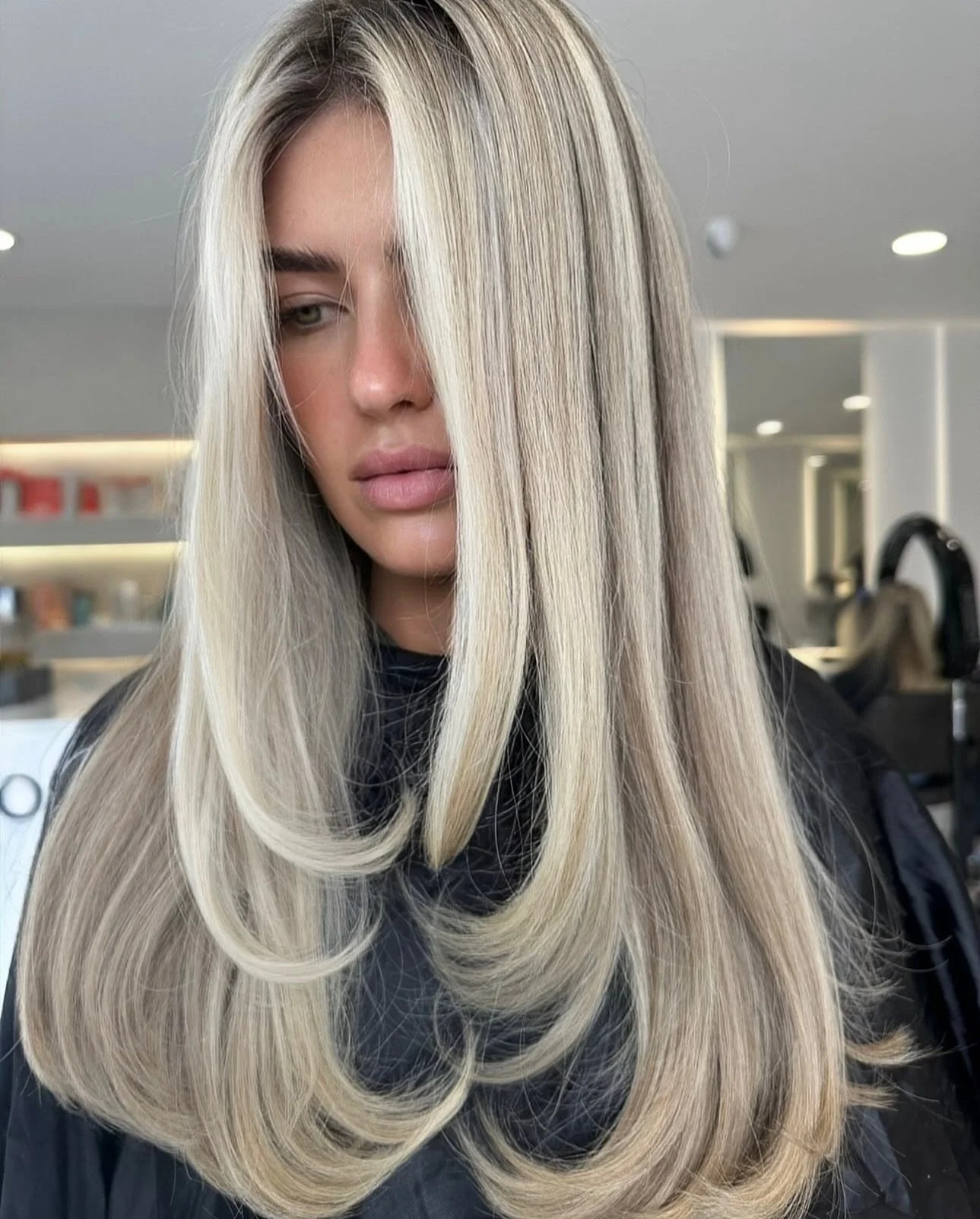 A woman with long, straight, blonde hair sitting in a salon.