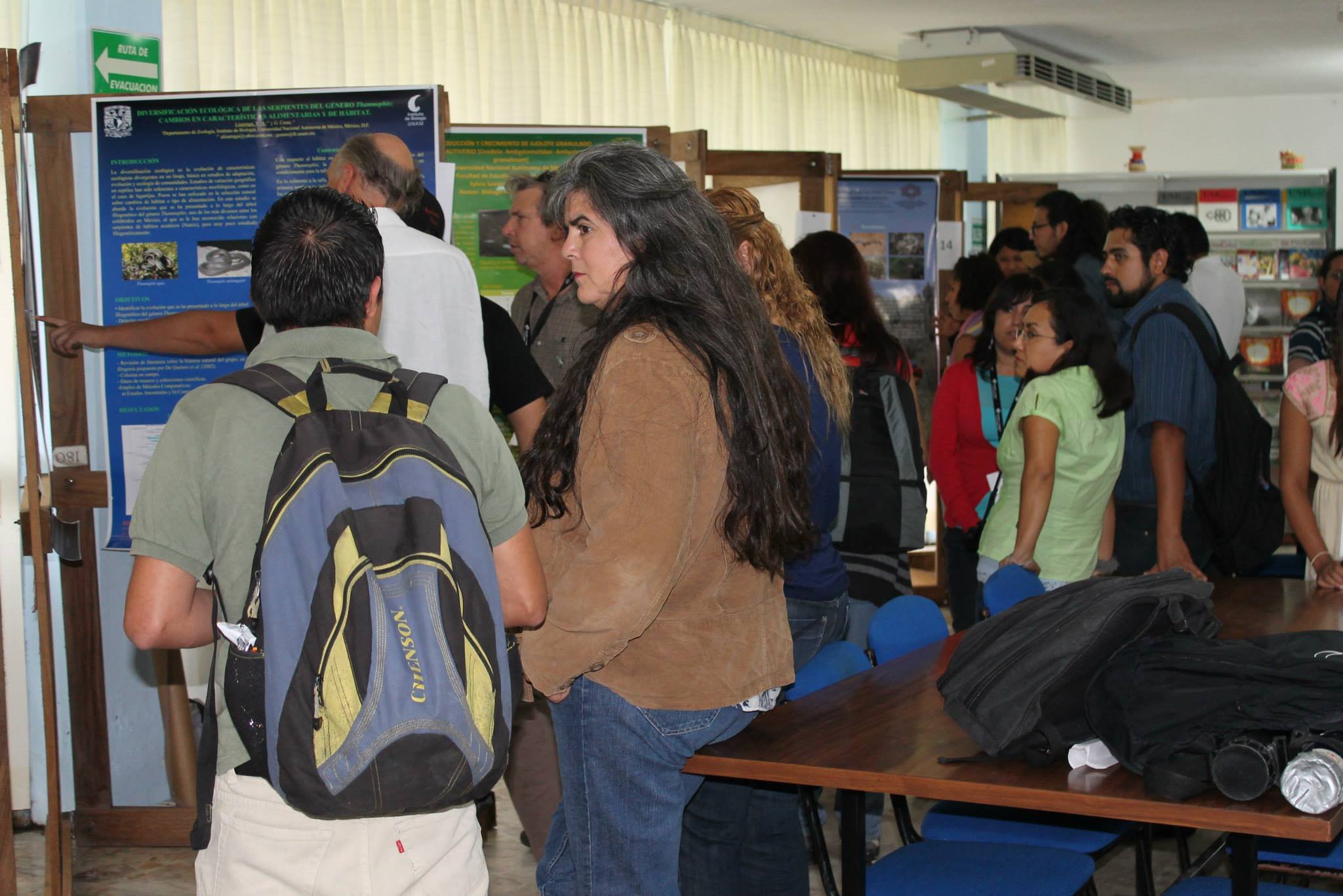 Grupo de personas en una feria científica observando carteles de investigación.