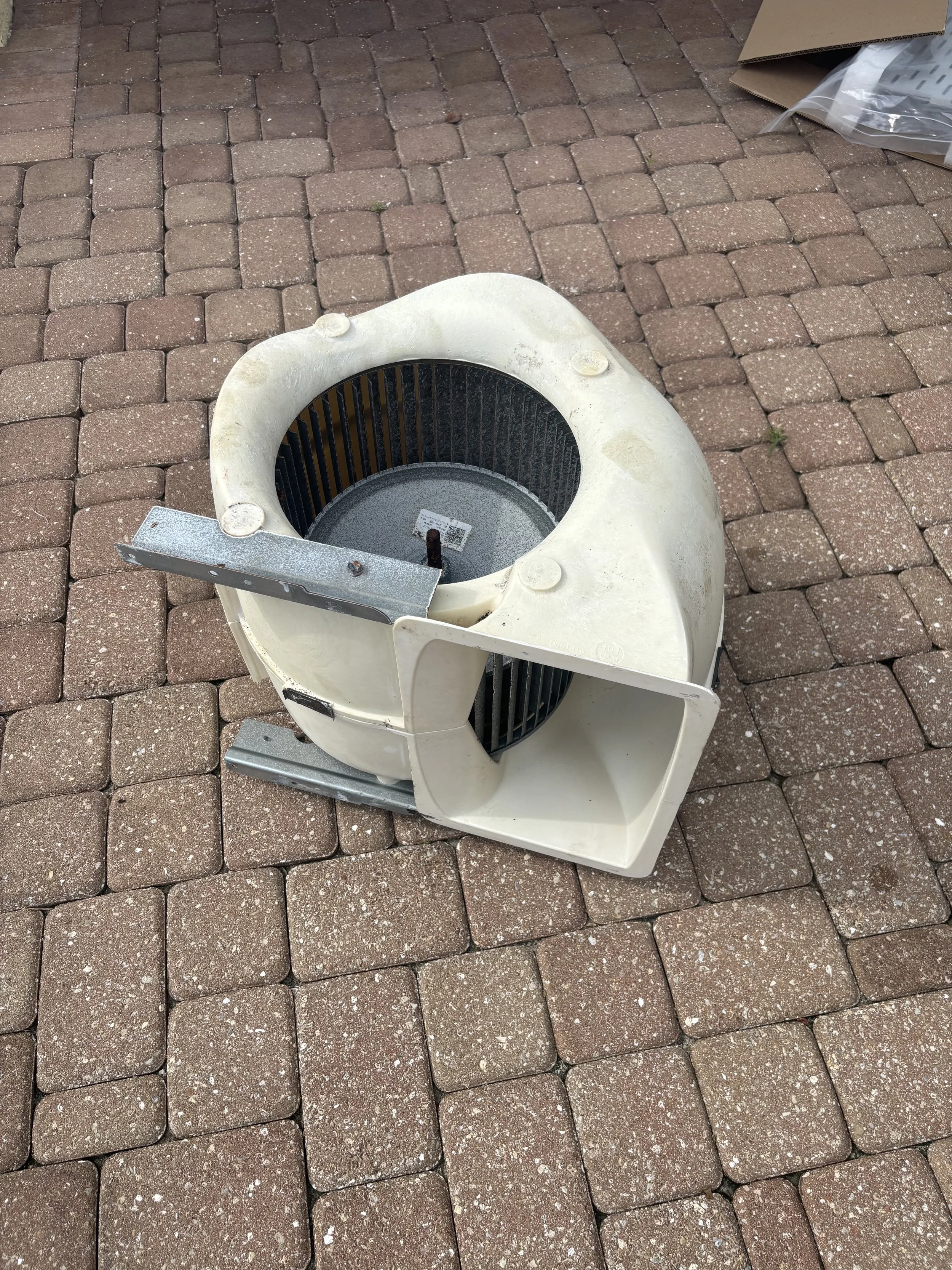 Broken or disassembled ceiling fan or ventilation impeller on brick paver ground.