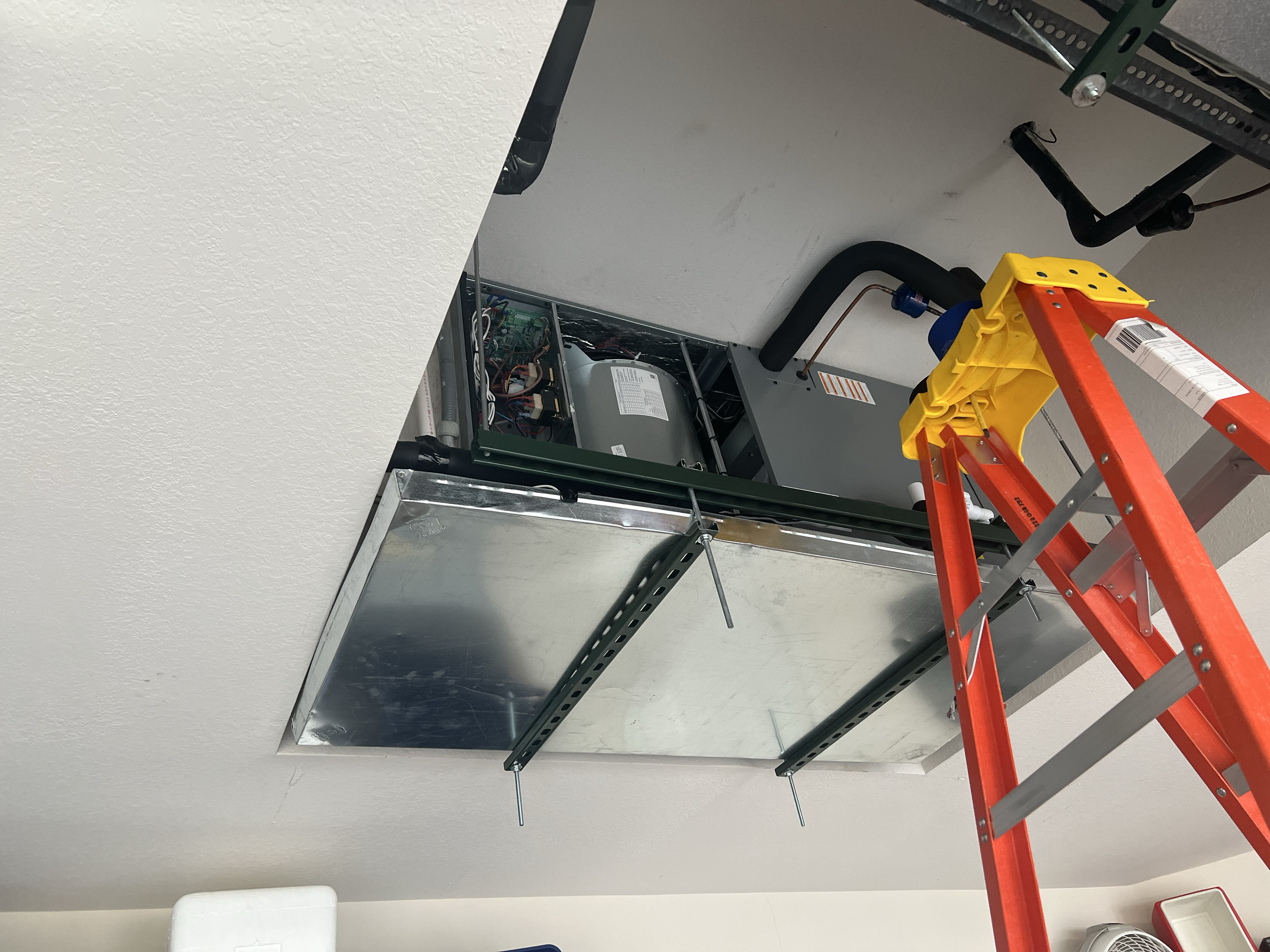 Ceiling with open HVAC access panel, orange ladder, and tools nearby.