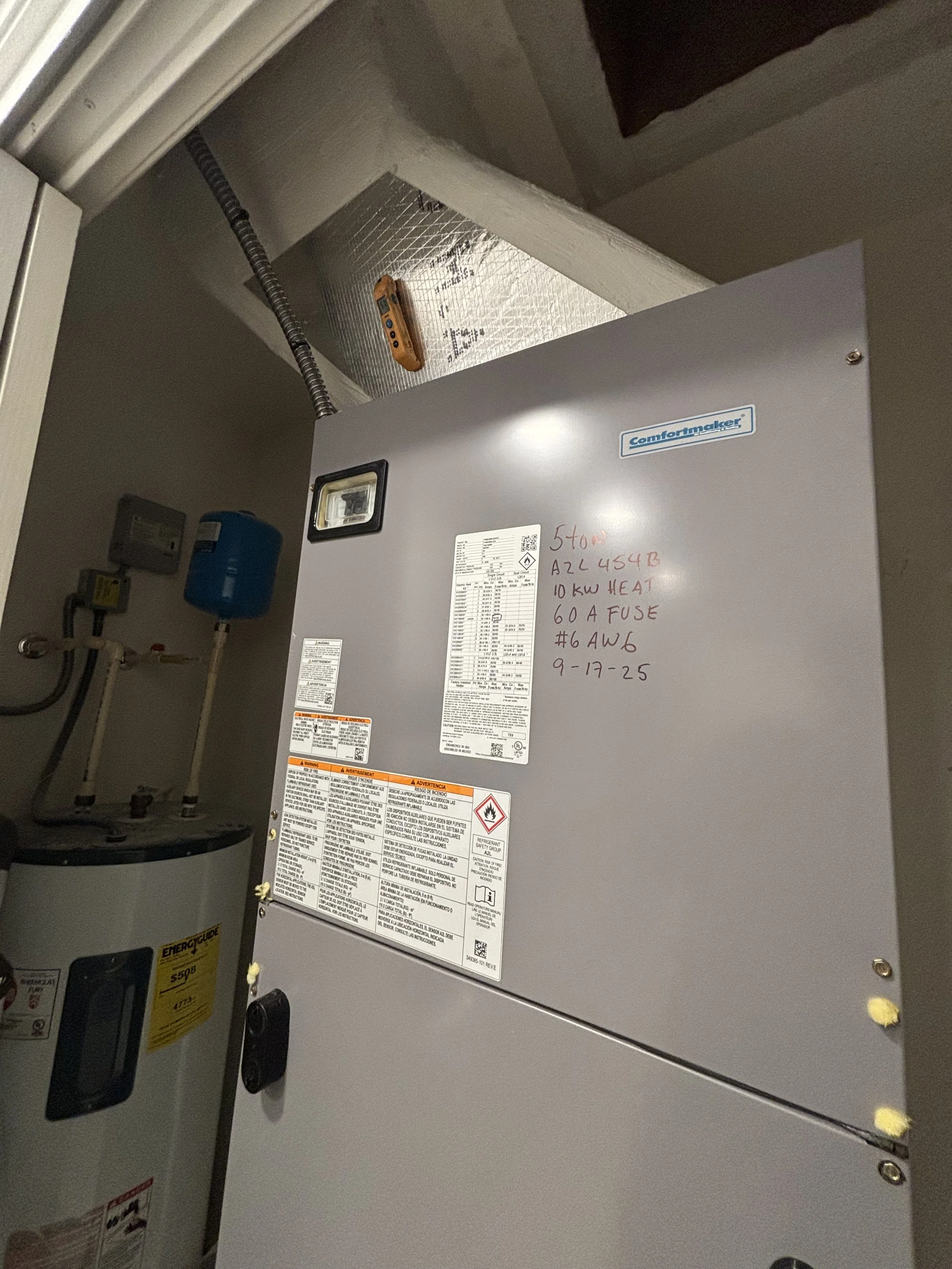 A commercial HVAC or electrical unit with handwritten notes, a flashlight, and a water heater tank nearby.