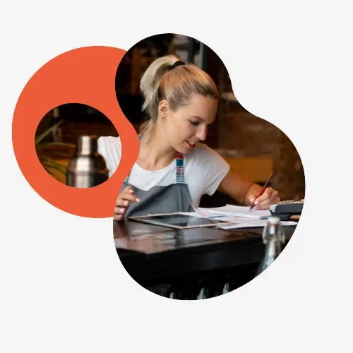 Hospitality bar owner reviewing paperwork and sales data on a tablet at the counter