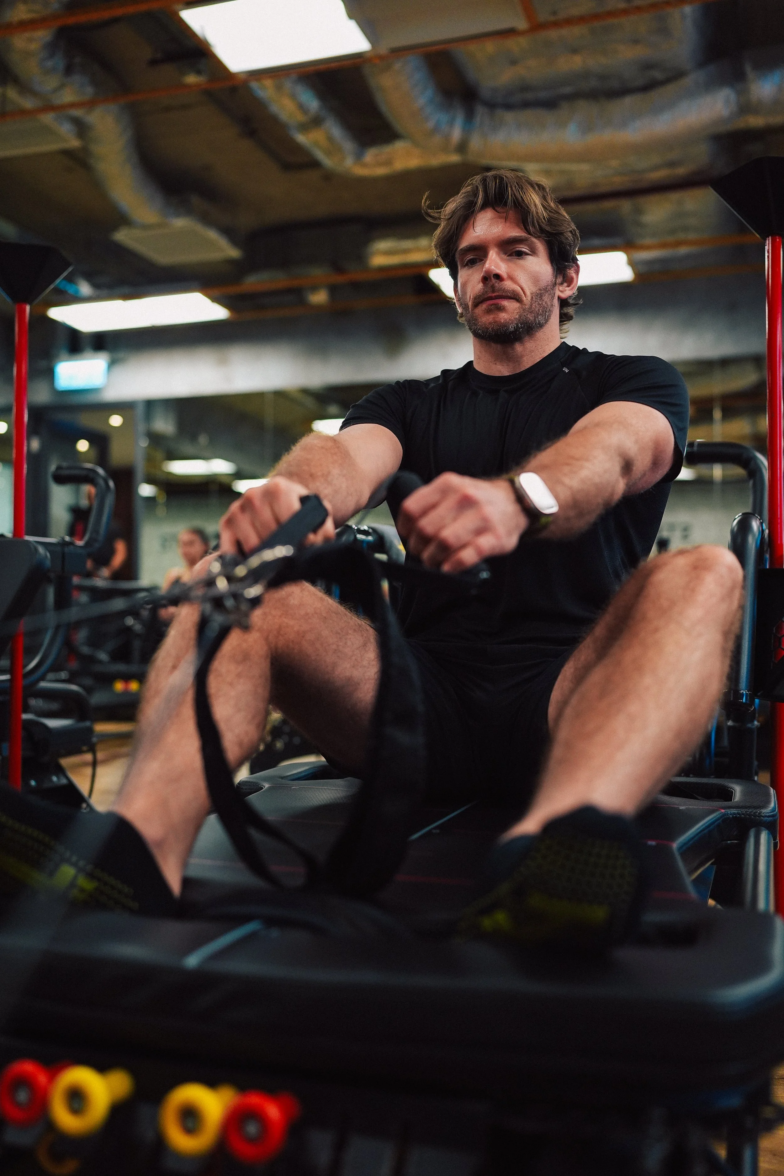 A man exercising on a rowing machine in a gym.