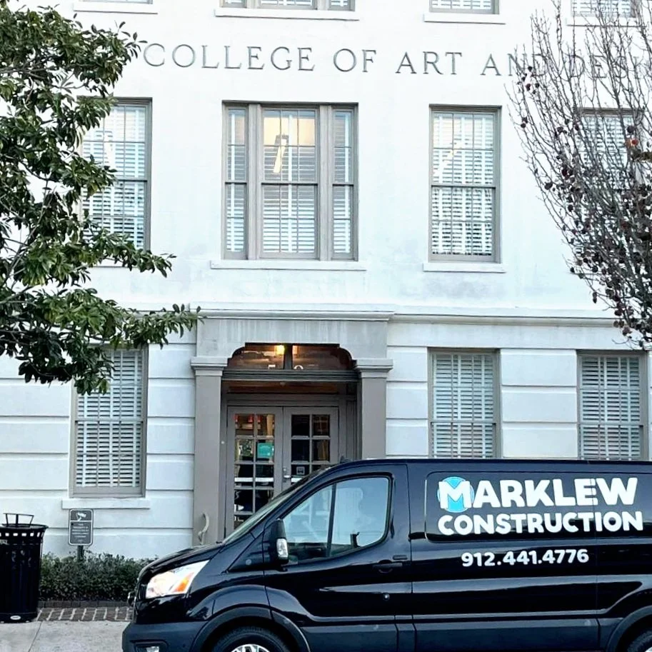Front view of a white building labeled 'Savannah College of Art and Design' with a black Marklew Construction van parked in front.