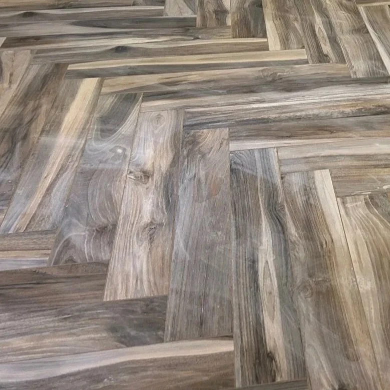 Close-up of wooden floor with a herringbone pattern, showing varying shades of brown and gray wood grains.