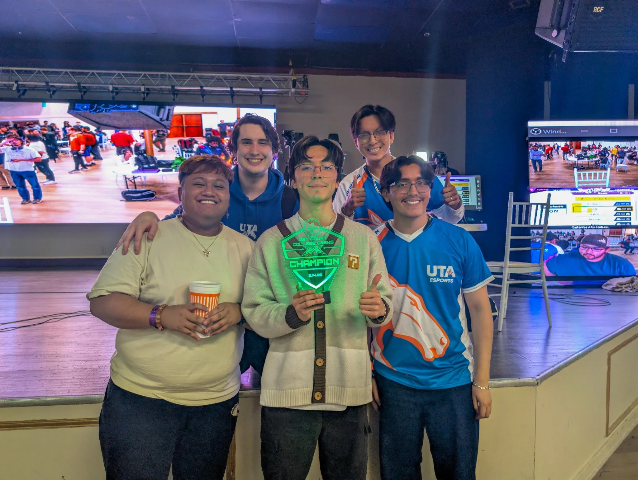 Five UT Arlington players holding the Texas Esports Collective College Crews champion trophy after a Super Smash Bros. Ultimate collegiate esports tournament in Austin, Texas